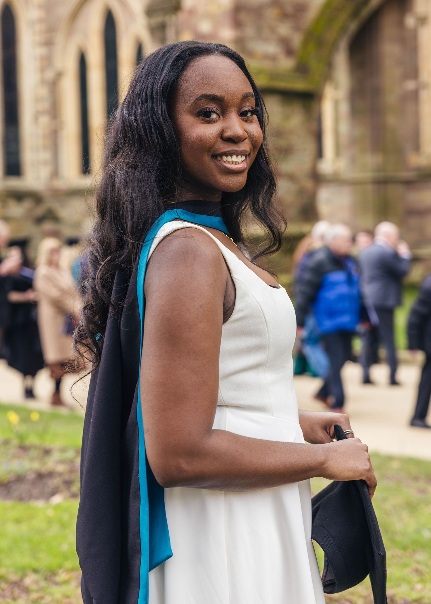 University graduate smiling in a gown during a graduation photoshoot by EvieSJPhotography.