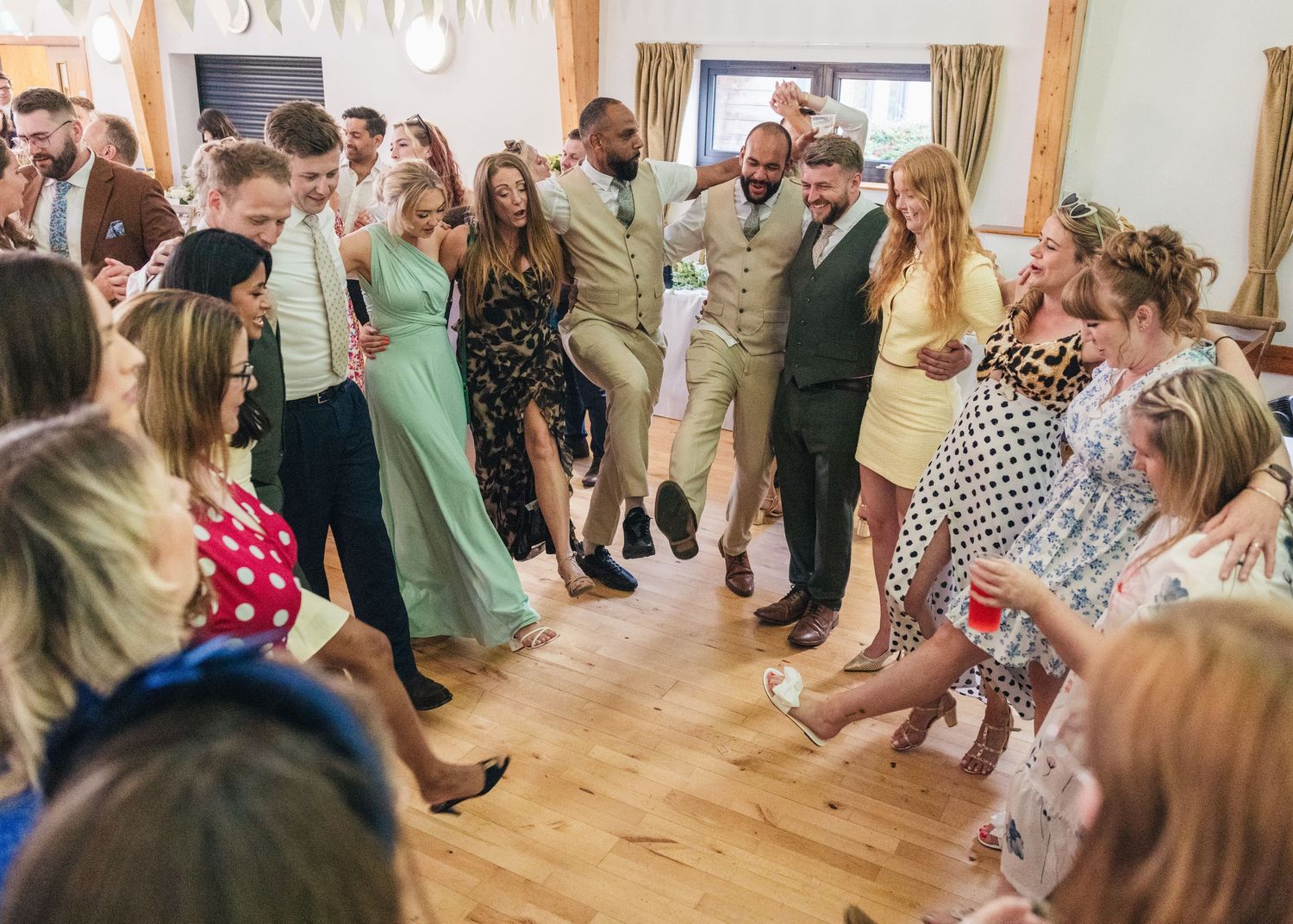 Jack and Aaron with their loved ones dancing in a circle on the dance floor at their Worcestershire wedding.