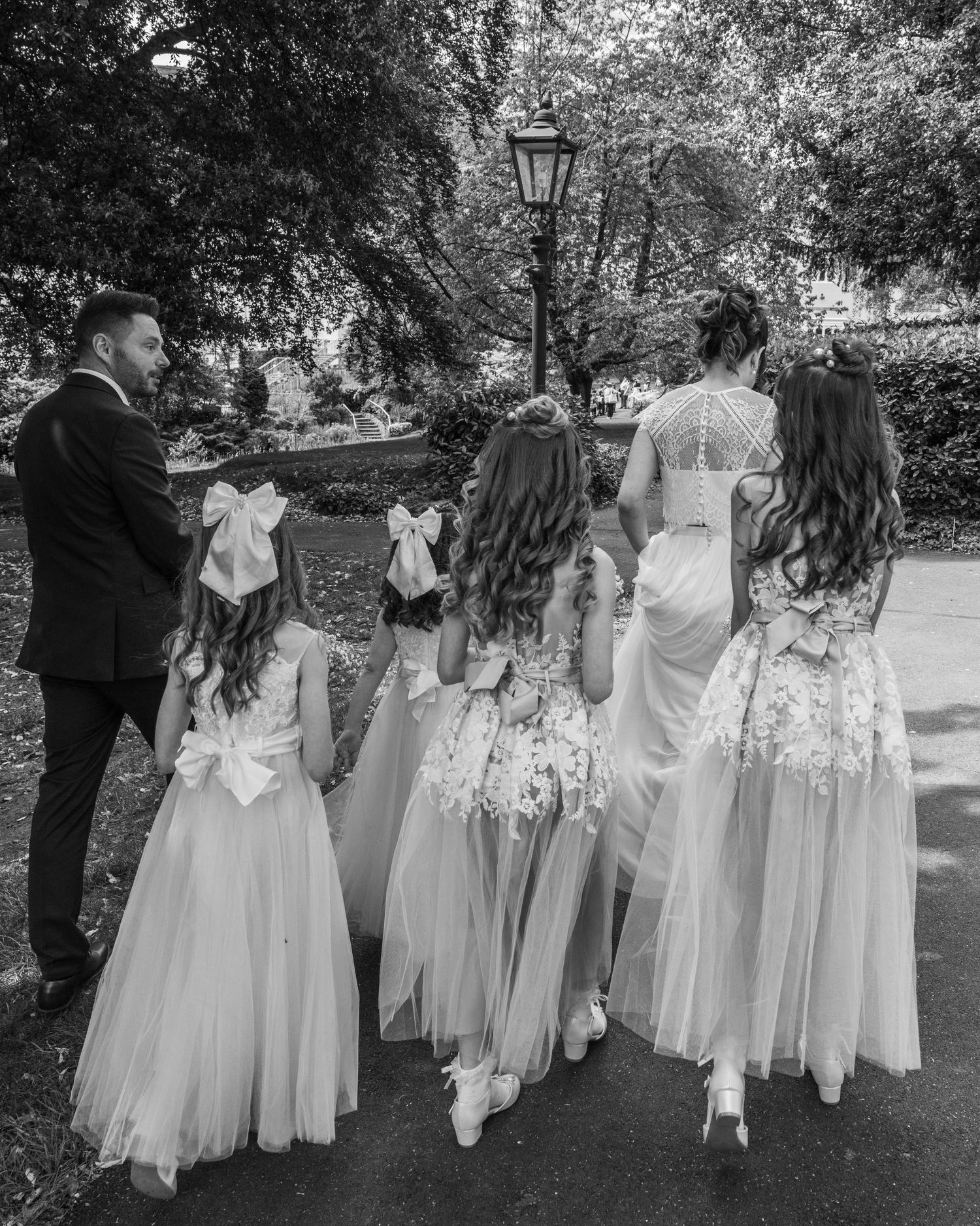 Bride and groom walking with their daughters to have group photos, captured by EvieSJPhotography.