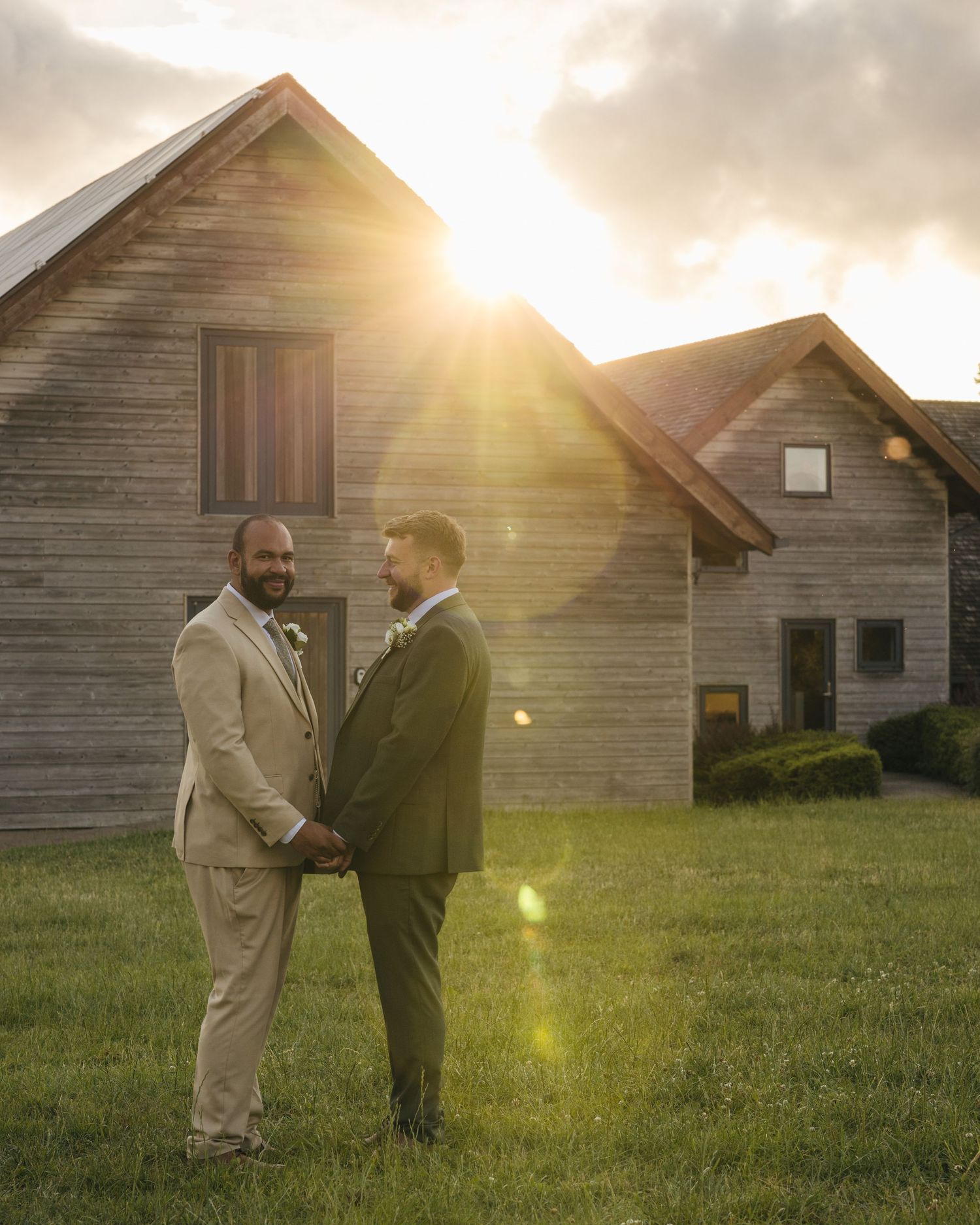 Aaron and Jack share a quiet embrace in front of Rock Village Hall during golden-hour wedding portraits.