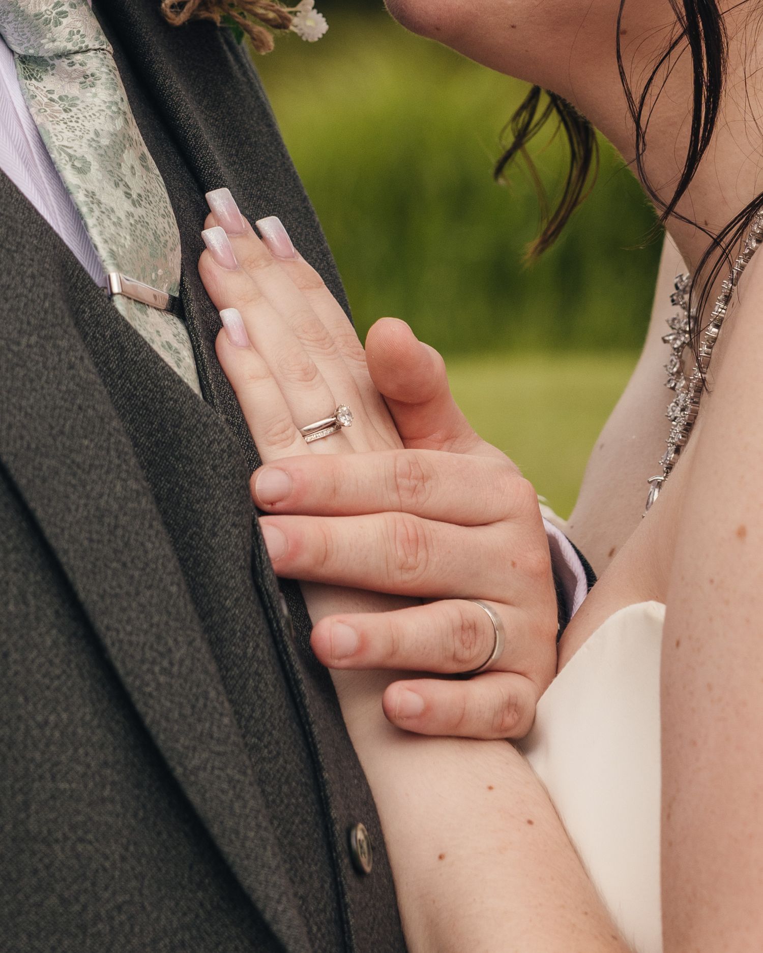 Close-up of Cortney and Dan's hands together, showing their wedding rings.