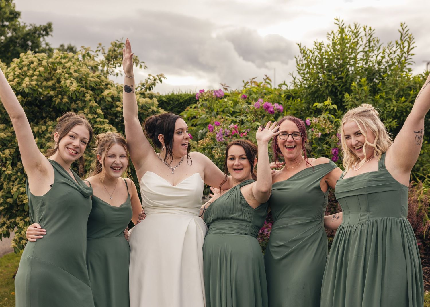 Cortney and her bridesmaids laughing and waving together in their green dresses.