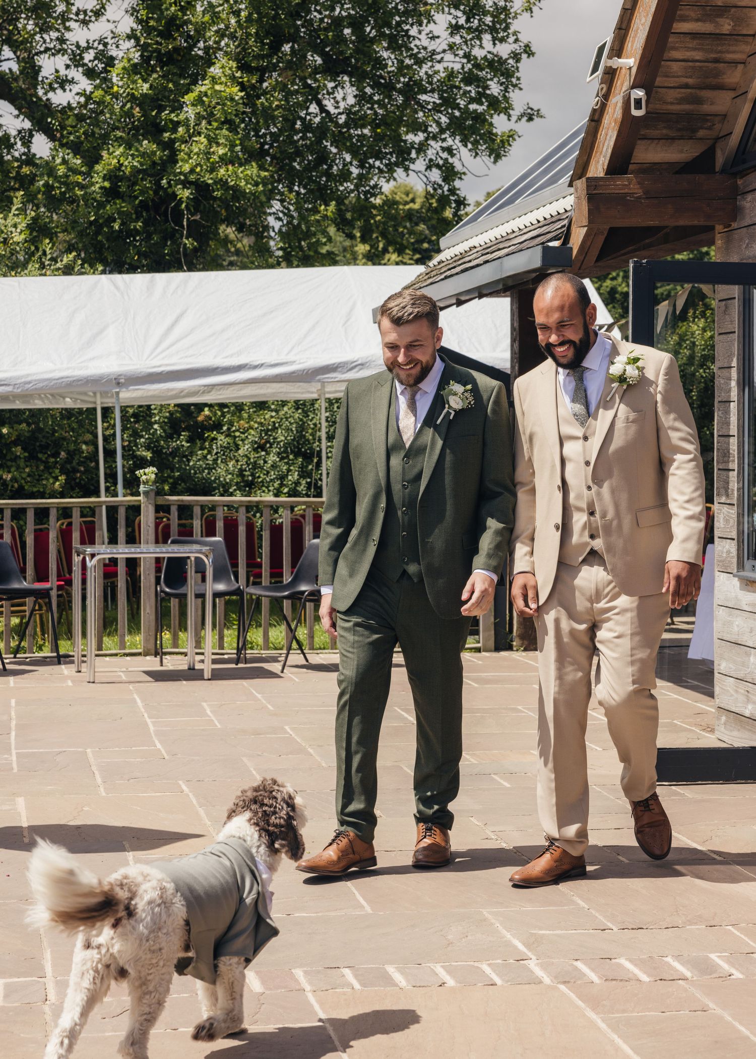 Aaron and Jack walk hand in hand with their dog Milo down the aisle at Rock Village Hall on their wedding day.