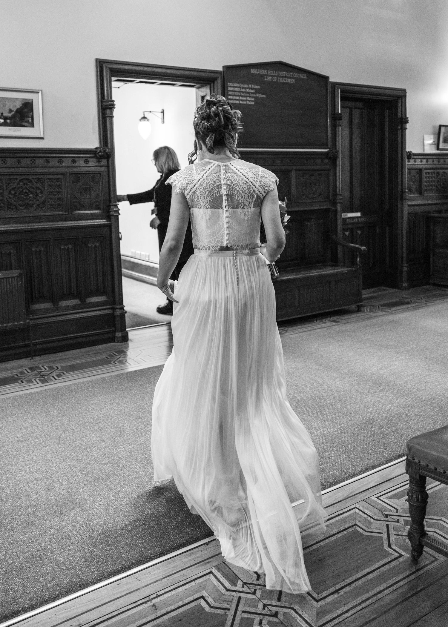 A bride walking into her wedding venue in black and white, captured by EvieSJPhotography.