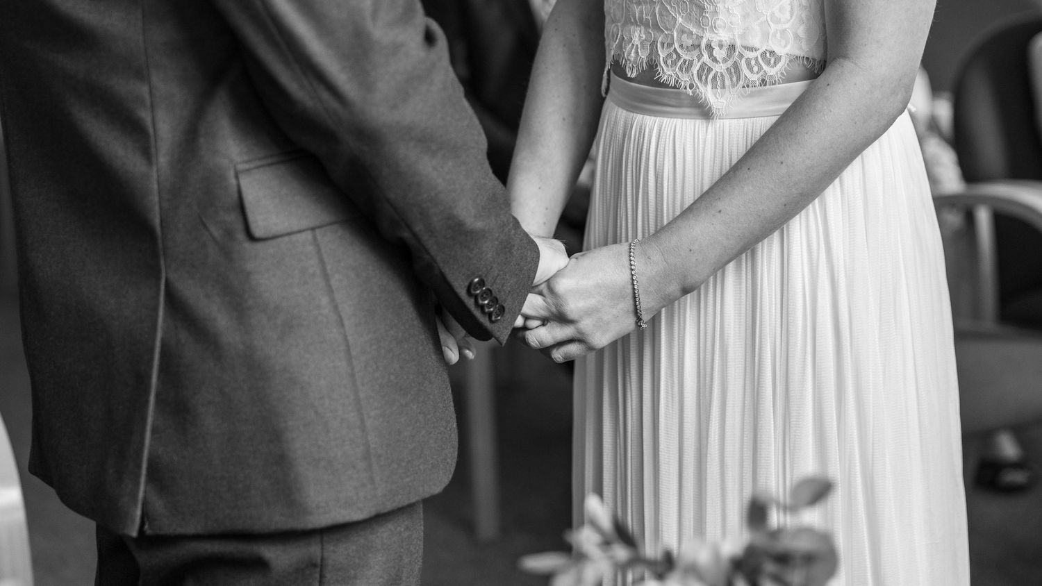 Bride and groom holding hands during their wedding ceremony, captured by EvieSJPhotography.