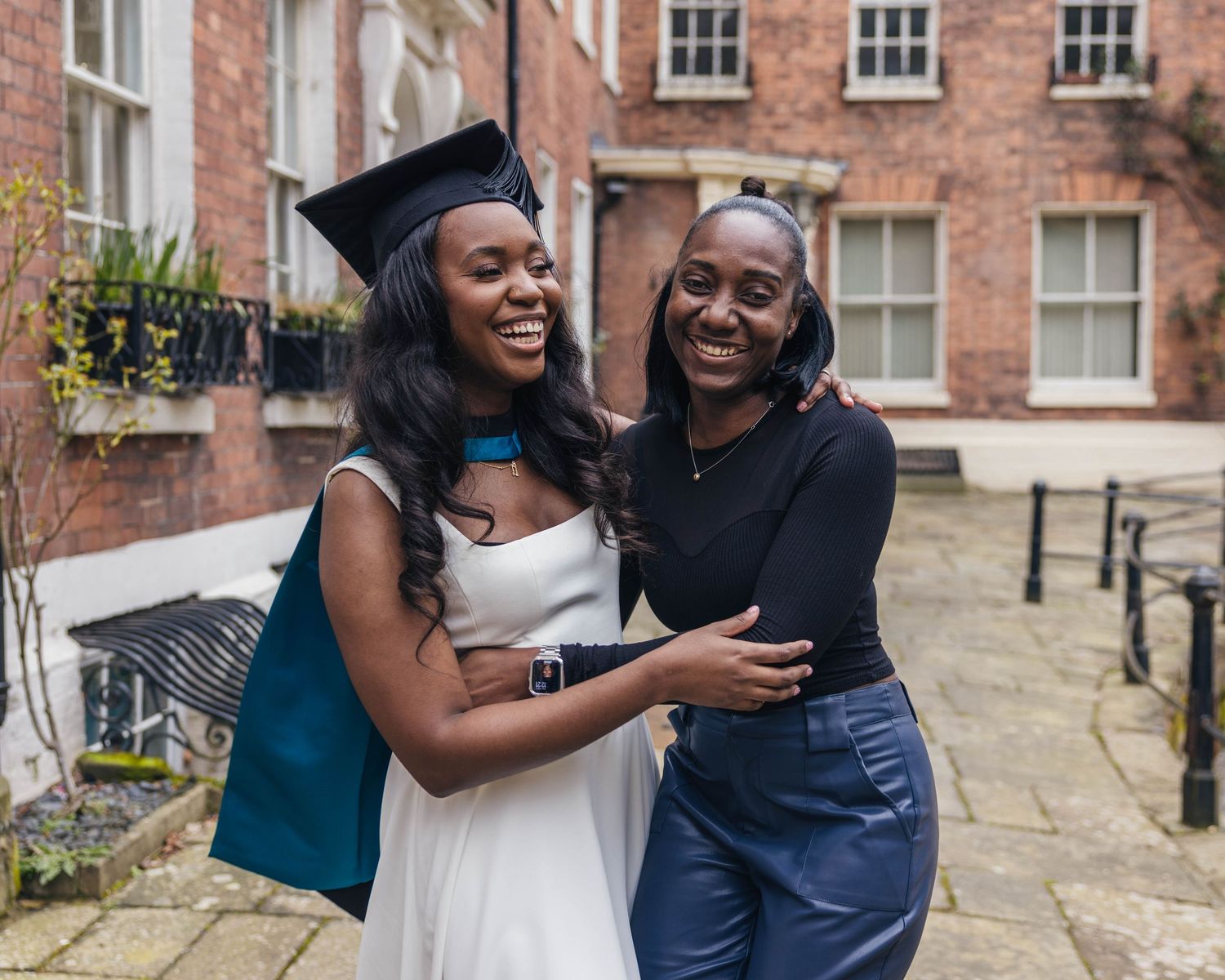 University graduate smiling in cap and gown during a graduation photoshoot with her family by EvieSJPhotography.