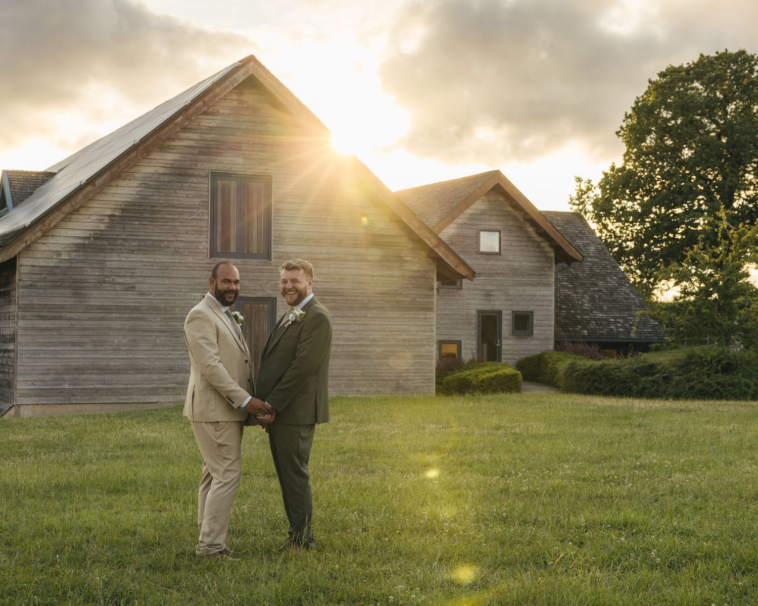 Aaron and Jack share a quiet embrace in front of Rock Village Hall during golden-hour wedding portraits.