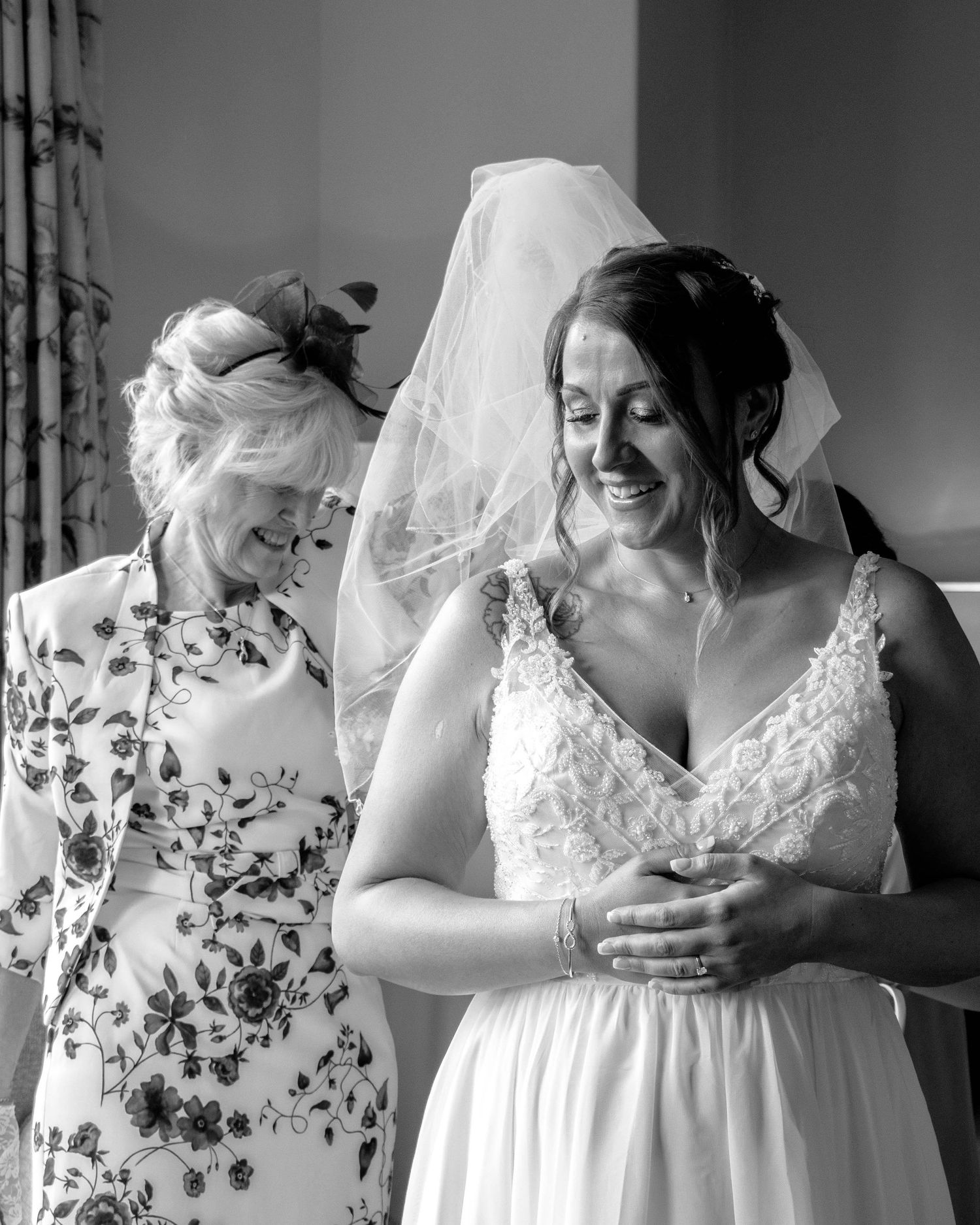 Bride and her mother attaching the bride's veil before walking down the aisle, captured by EvieSJPhotography.