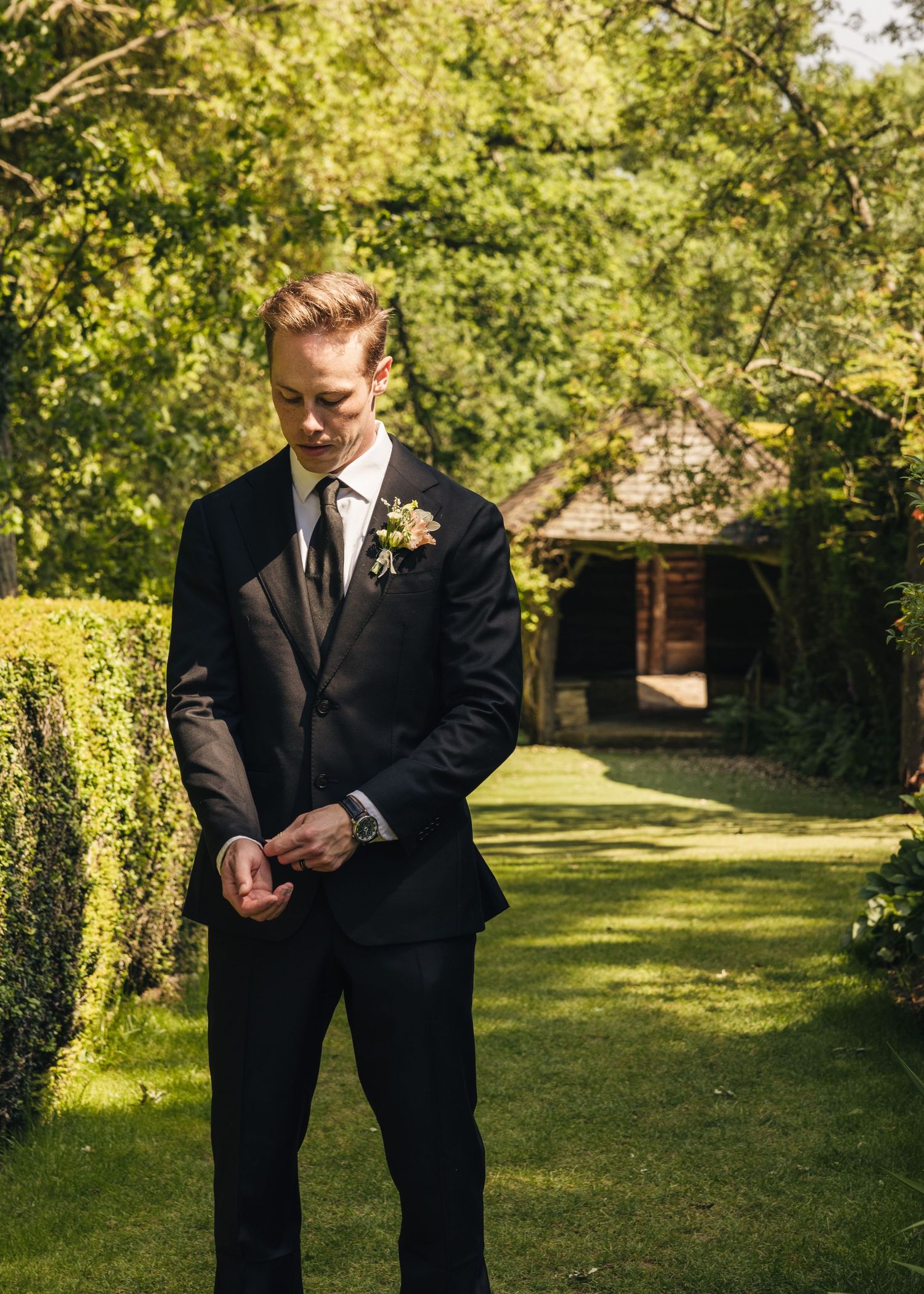 Groom fixing his cufflinks during a solo photoshoot on his wedding day, captured by EvieSJPhotography.