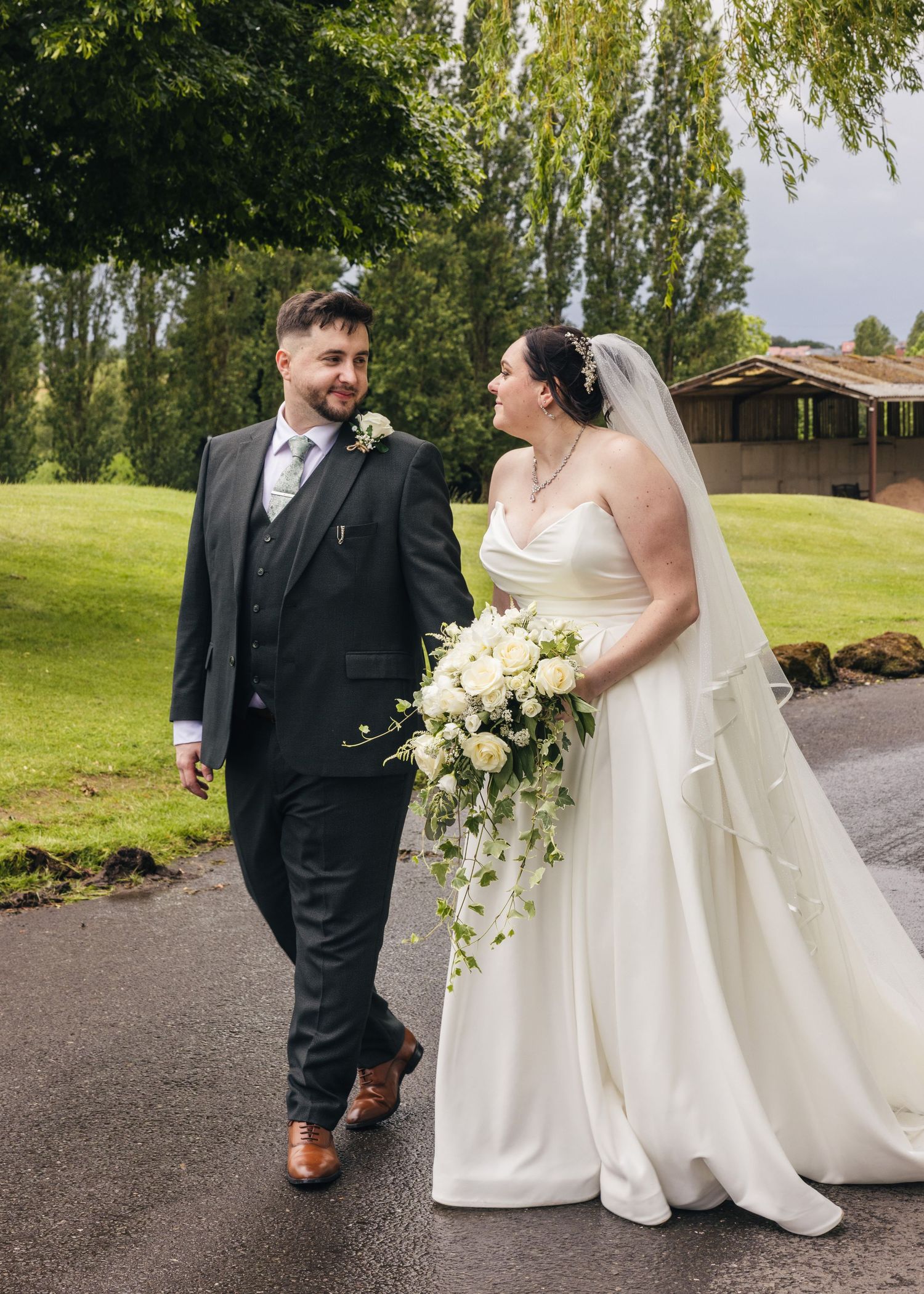 Cortney and Dan walking together across the grounds during their Windmill Village Hotel wedding portraits.