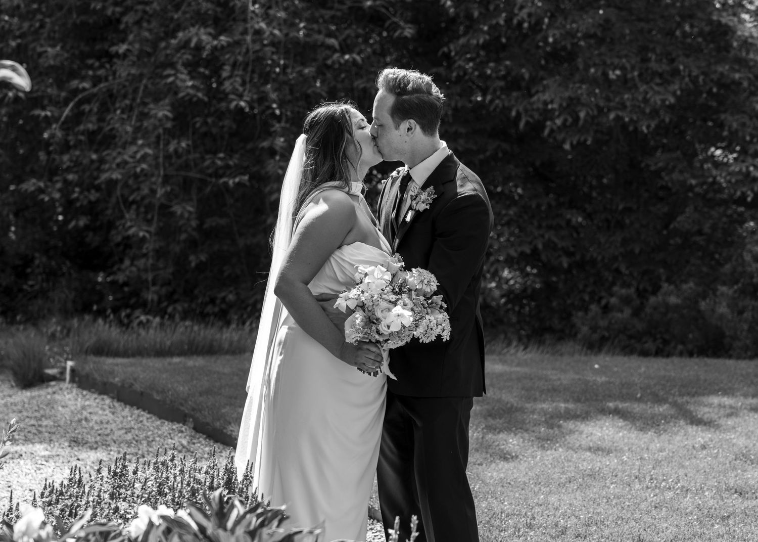 A bride and groom sharing a romantic kiss on their wedding day, captured by EvieSJPhotography.