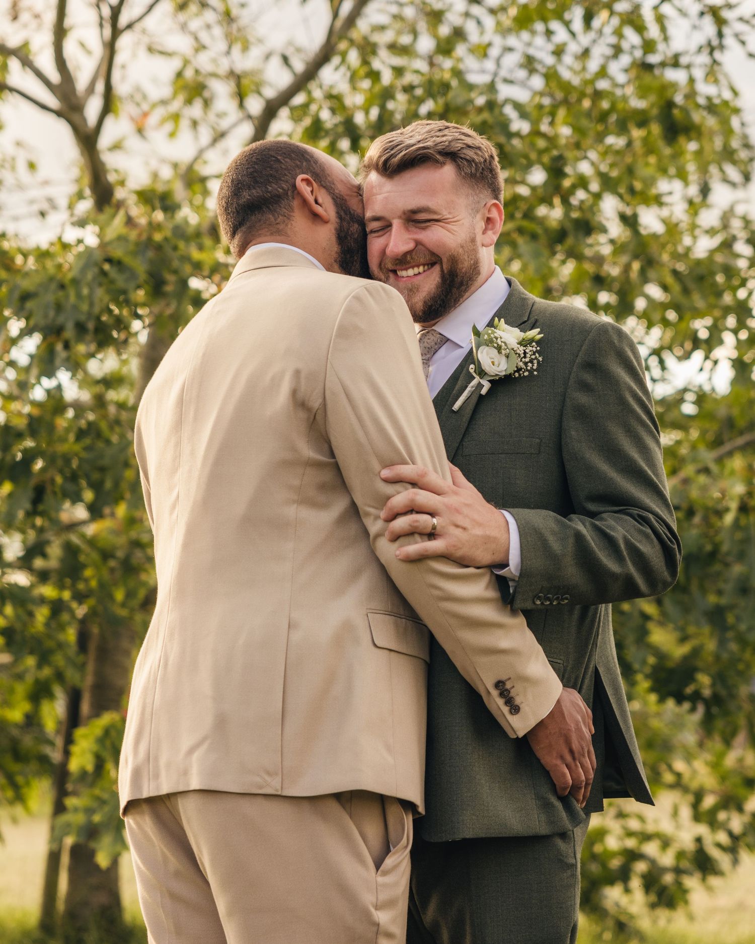 Aaron and Jack share a quiet embrace beneath a tree during golden-hour wedding portraits at Rock Village Hall.