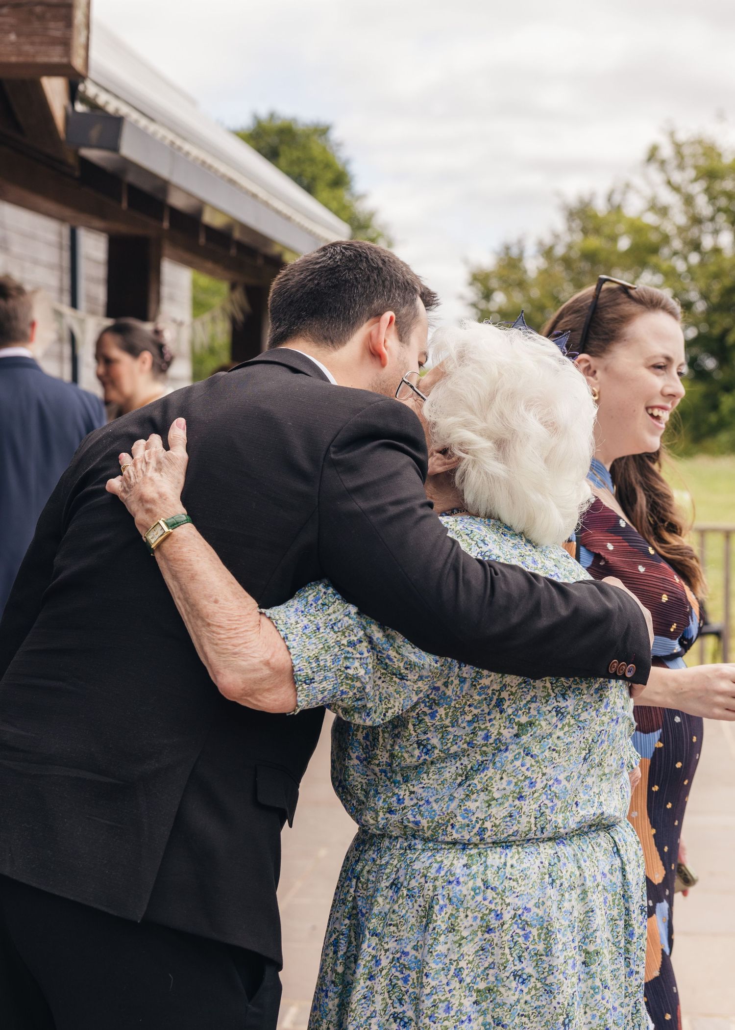 An older landing embracing a younger wedding guest at the wedding drinks reception in Worcestershire.