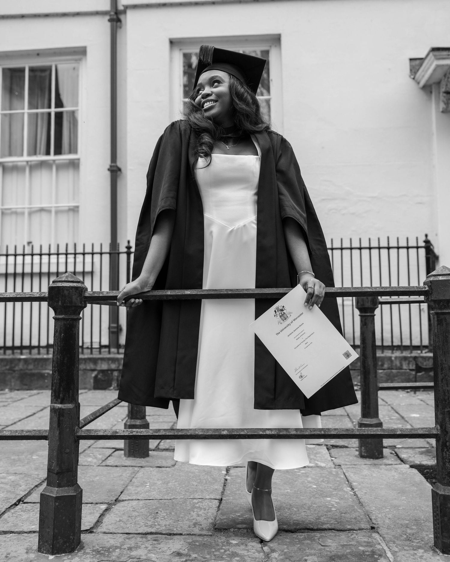 University graduate smiling in cap and gown during a graduation photoshoot by EvieSJPhotography.