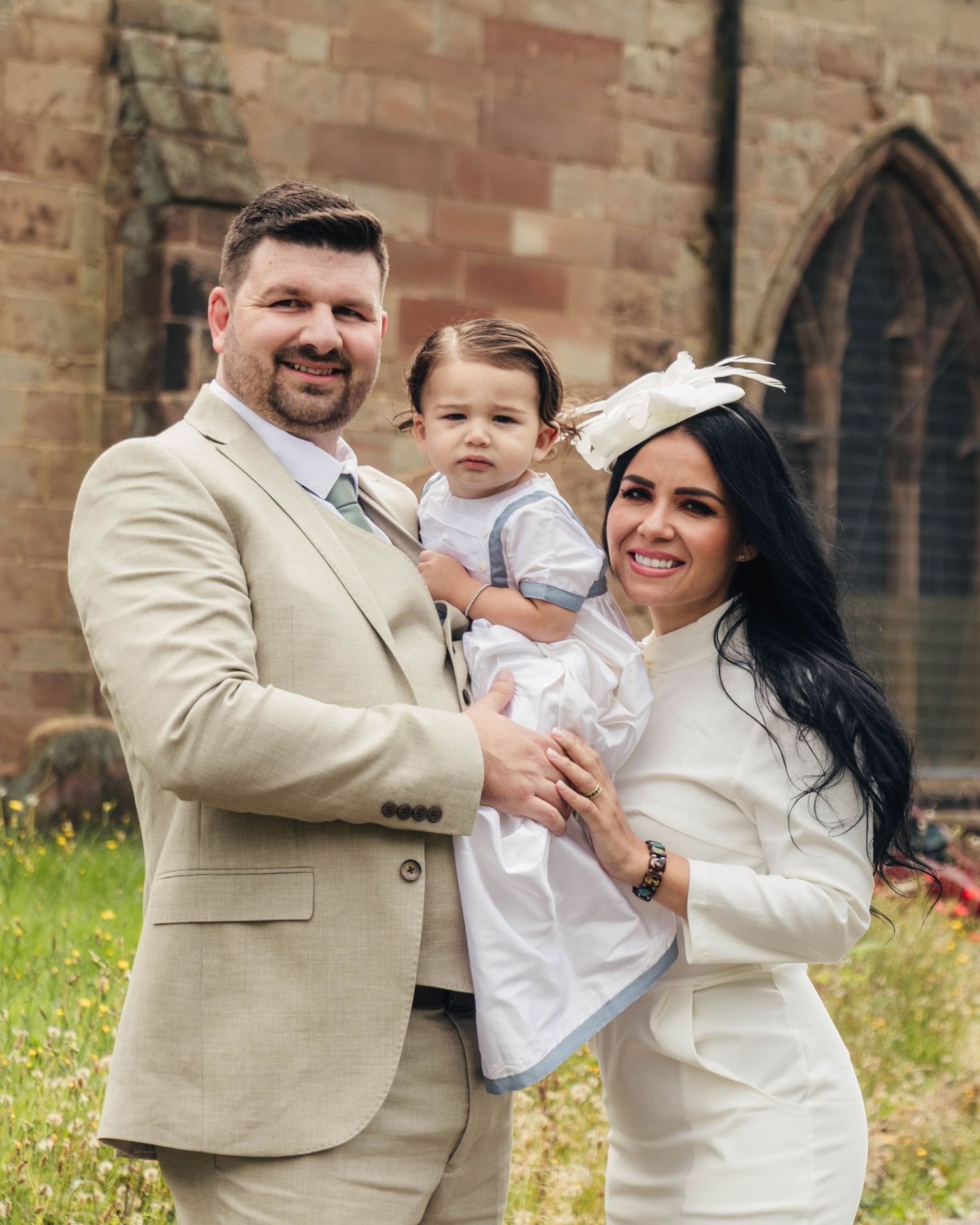 A couple and their son, outside a church after his Christening, captured in a natural style by EvieSJPhotography.