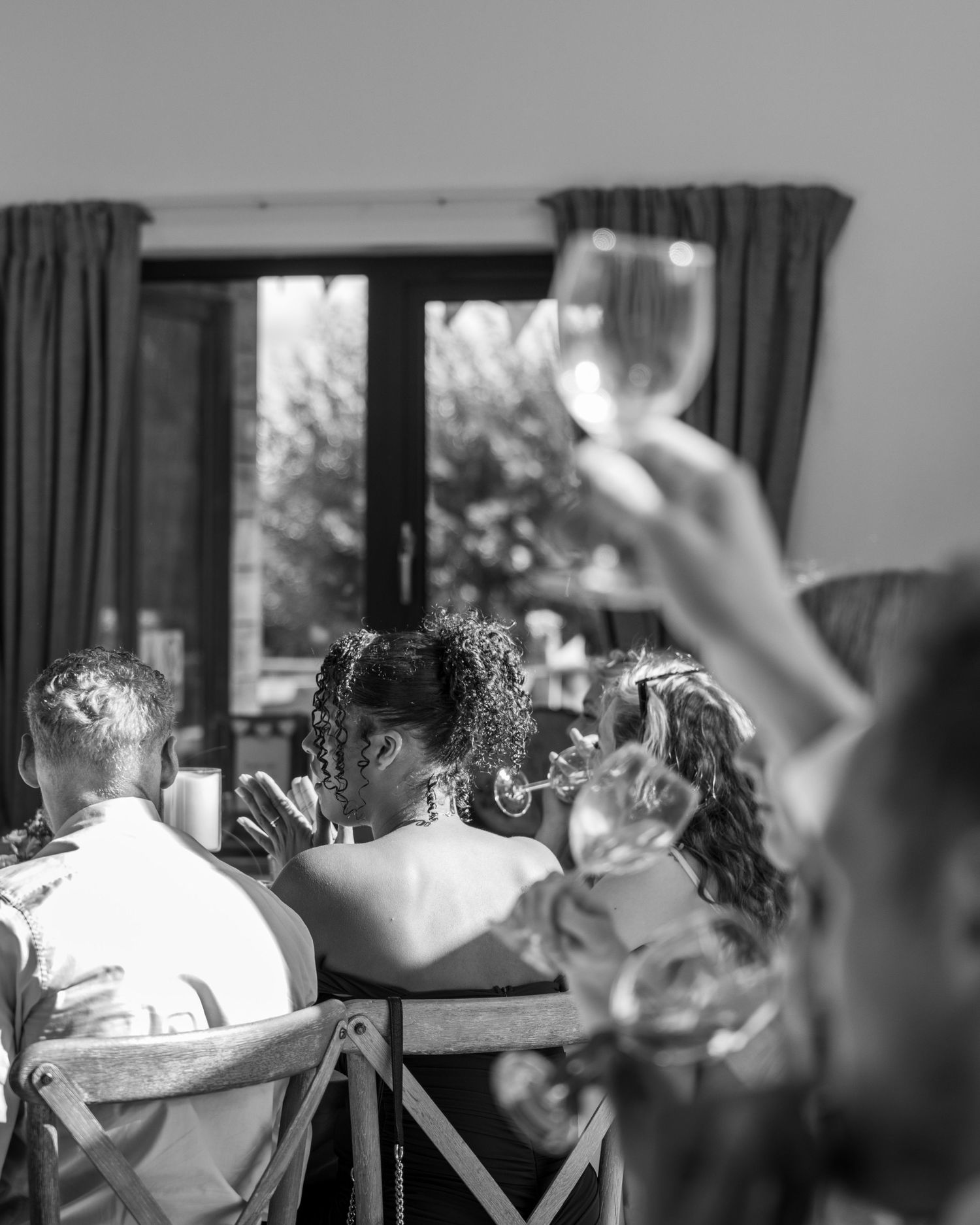 A black and white artistic photograph of guests celebrating during the speeches.
