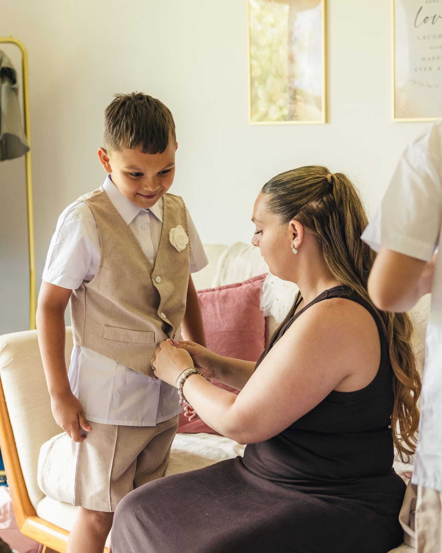 A mother helping her son with his waistcoat in preparation for a wedding at Rock Village Hall.