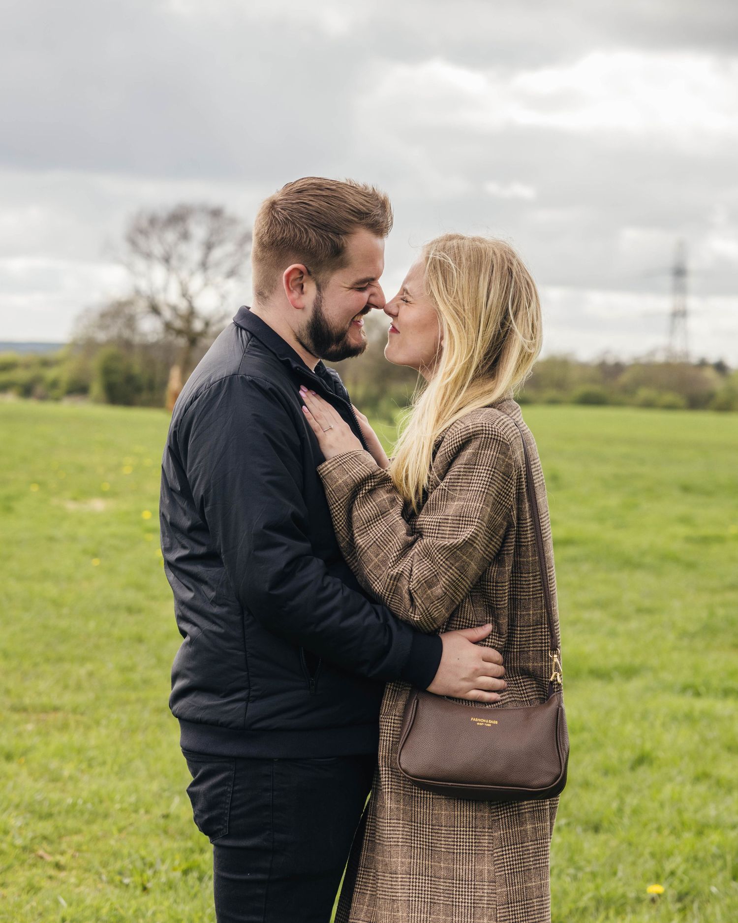 Natural engagement photoshoot of a couple in a field by EvieSJPhotography.