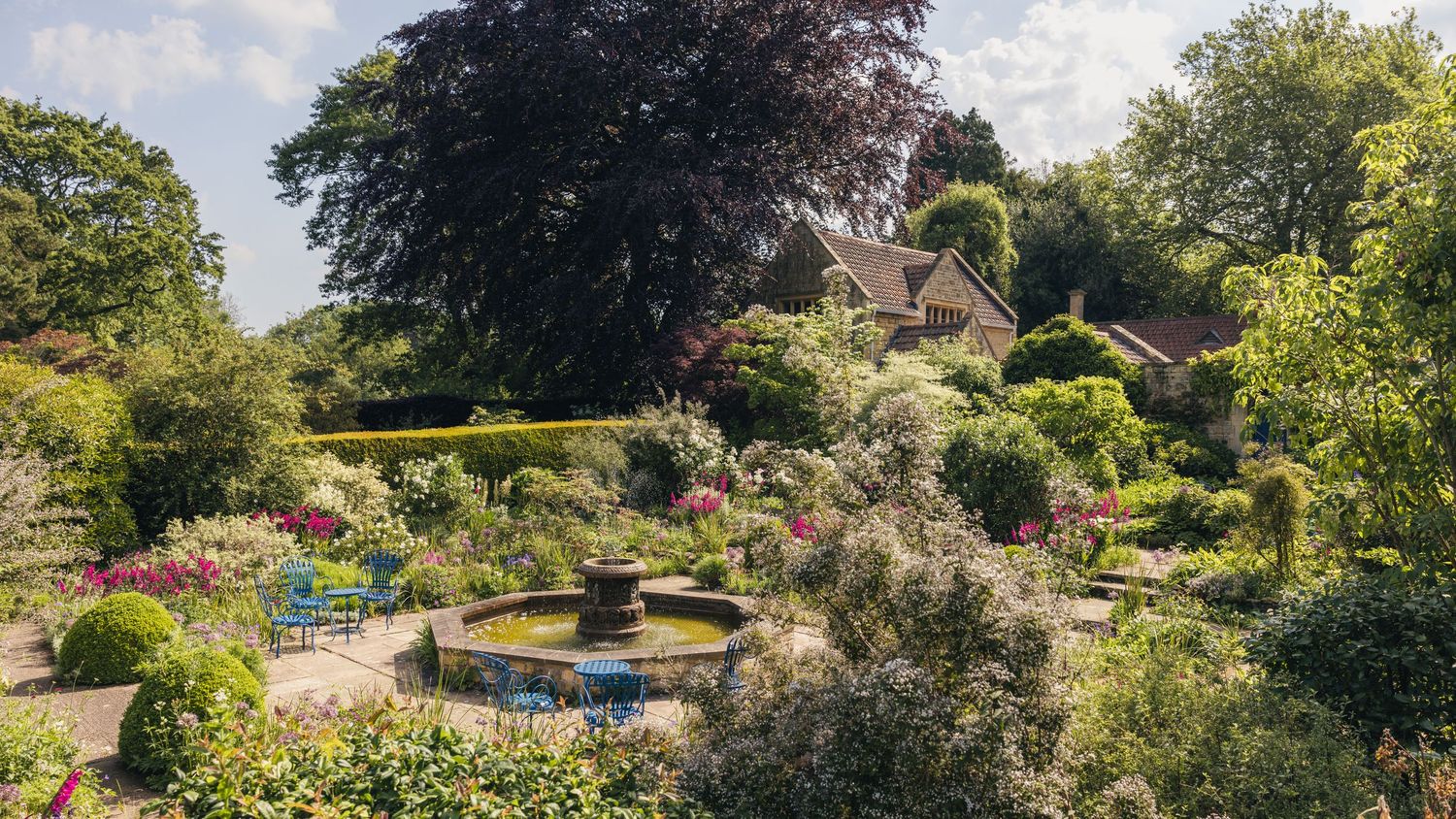 Beautiful scenery of a wedding venue featuring a fountain and lots of greenery and flows, captured by EvieSJPhotography.