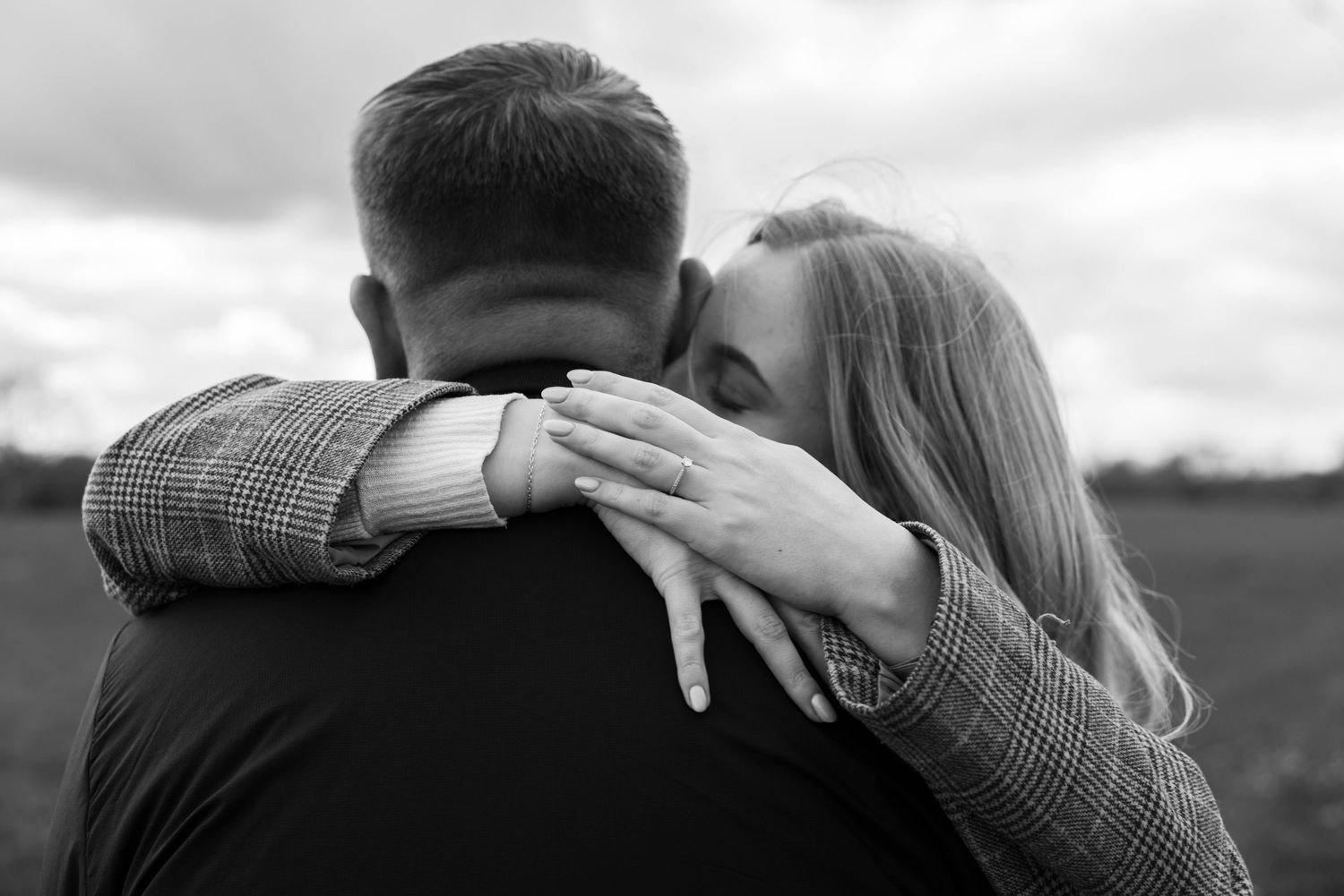 A couple hugging during their engagement session, in black and white, captured by EvieSJPhotography.
