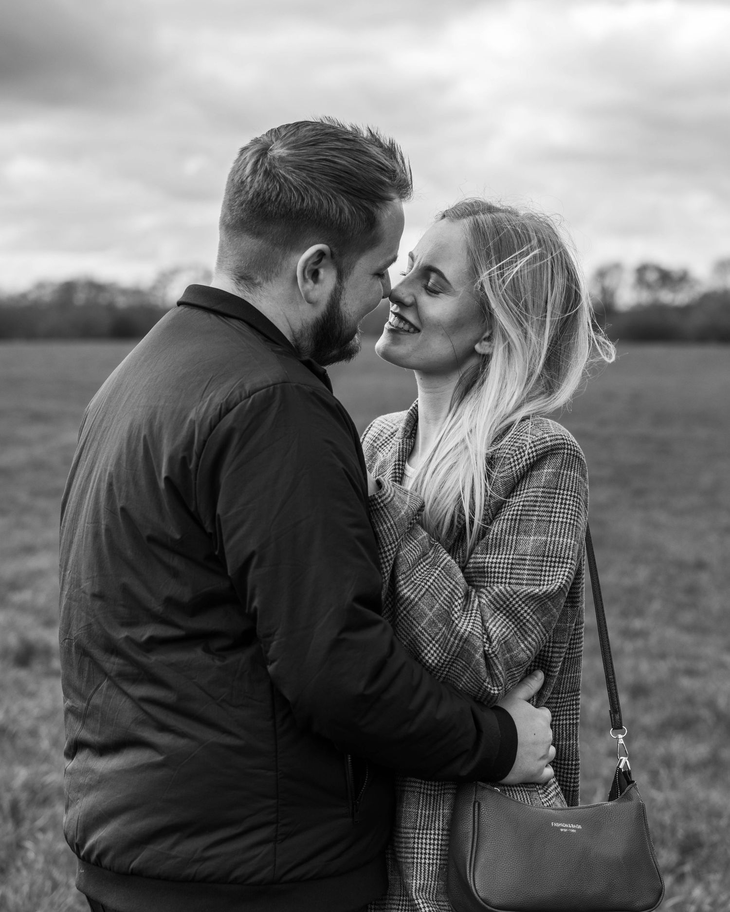 Natural black and white engagement photoshoot of a couple in a field by EvieSJPhotography.