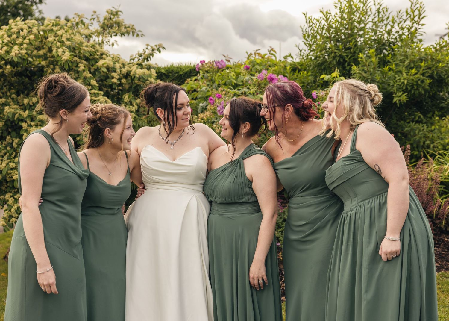 Cortney and her bridesmaids laughing and waving together in their green dresses.