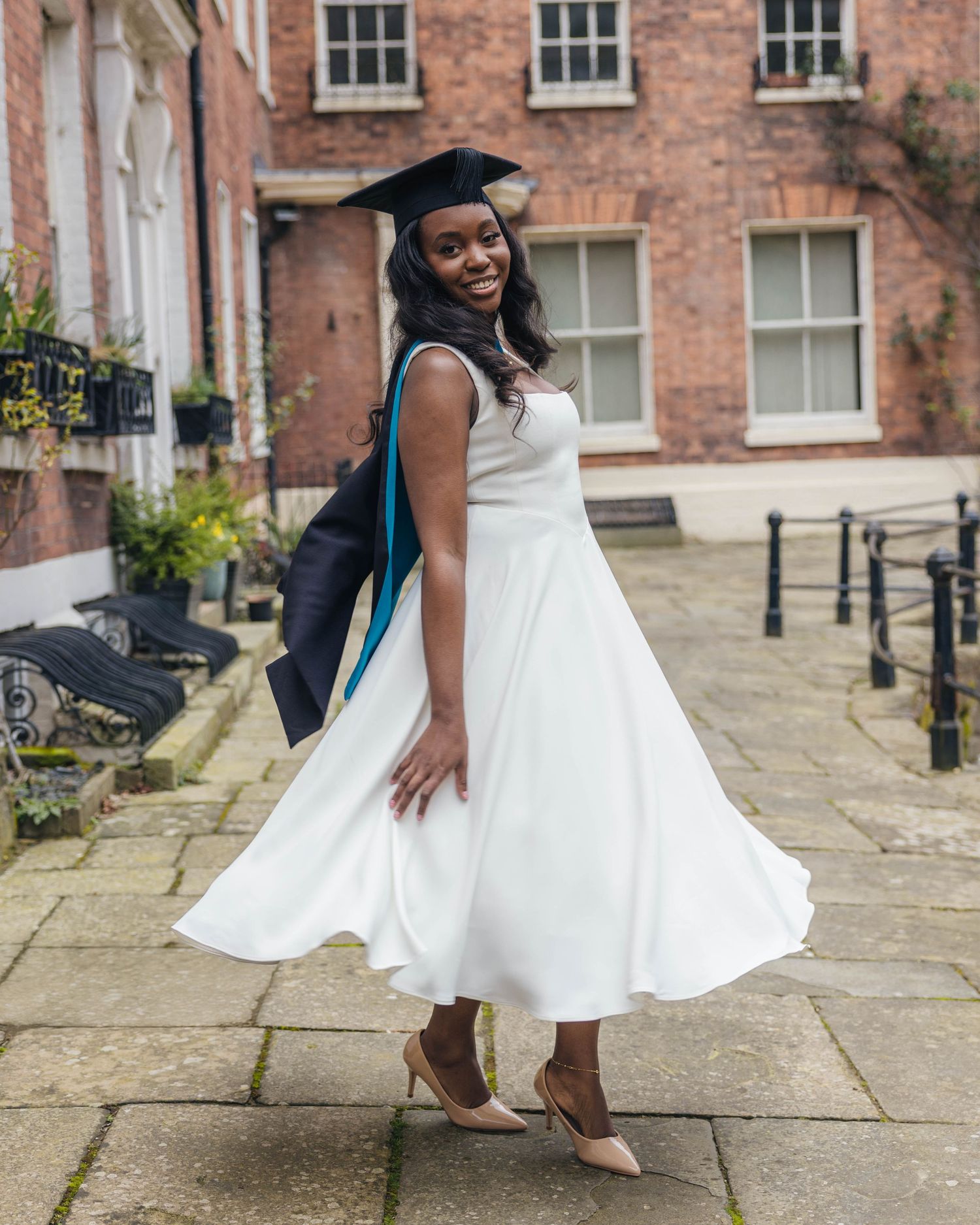 University graduate smiling in cap and gown during a graduation photoshoot by EvieSJPhotography.