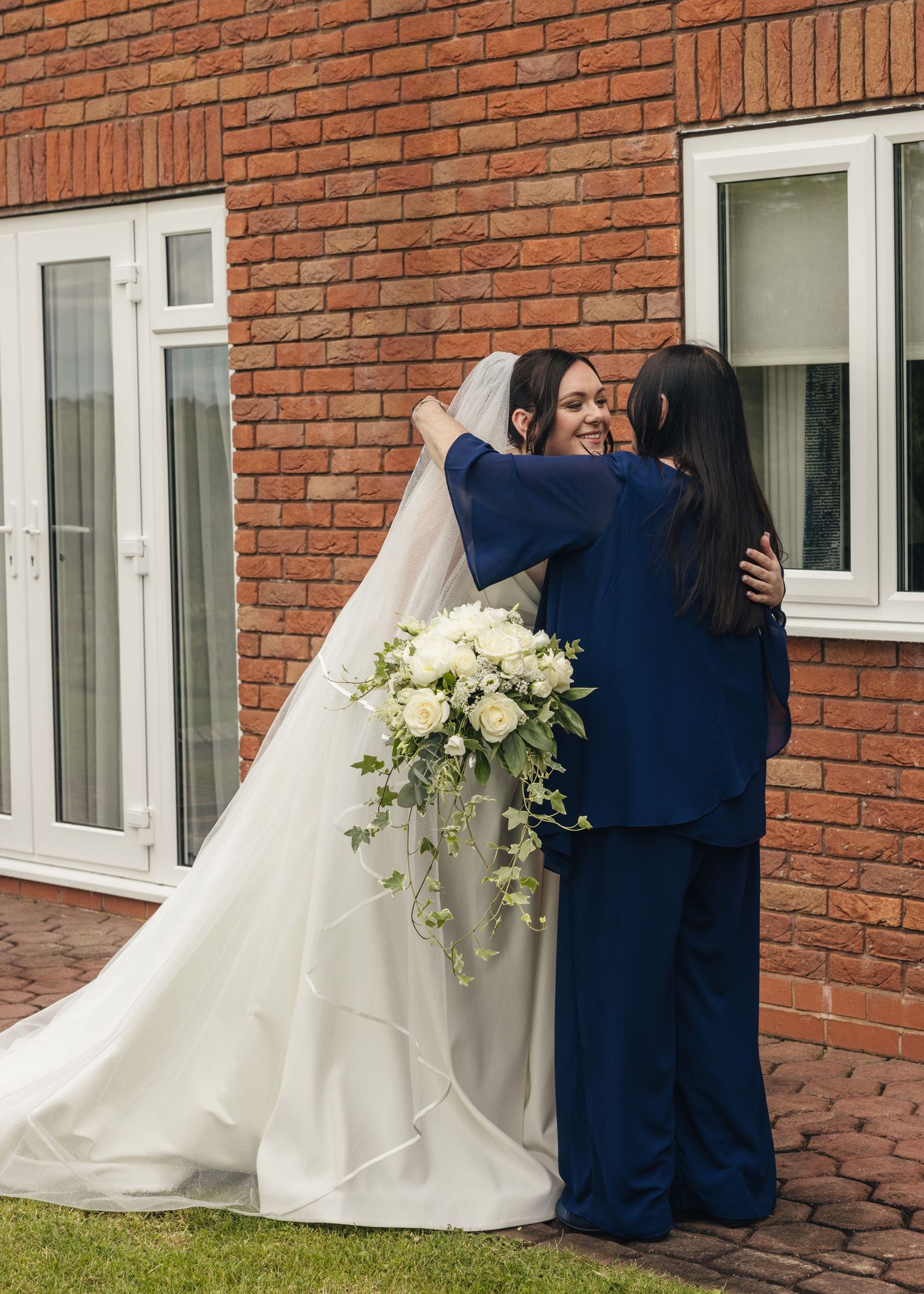 Candid photograph of Cortney hugging her grandmother in a blue outfit outside the wedding venue.