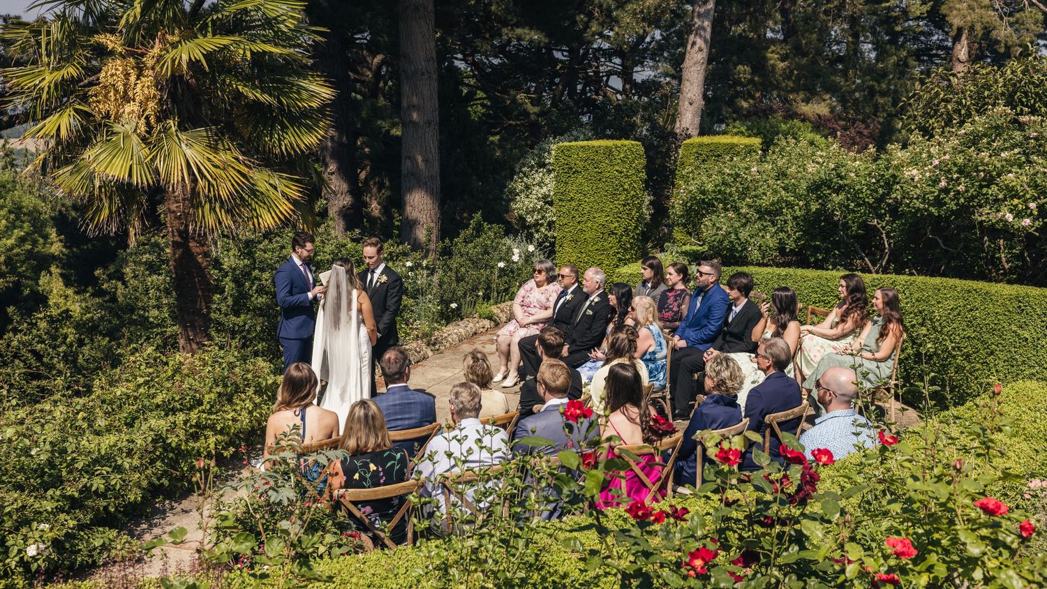 Mid-ceremony, the bride and groom surrounded by all their loved ones, captured by EvieSJPhotography.