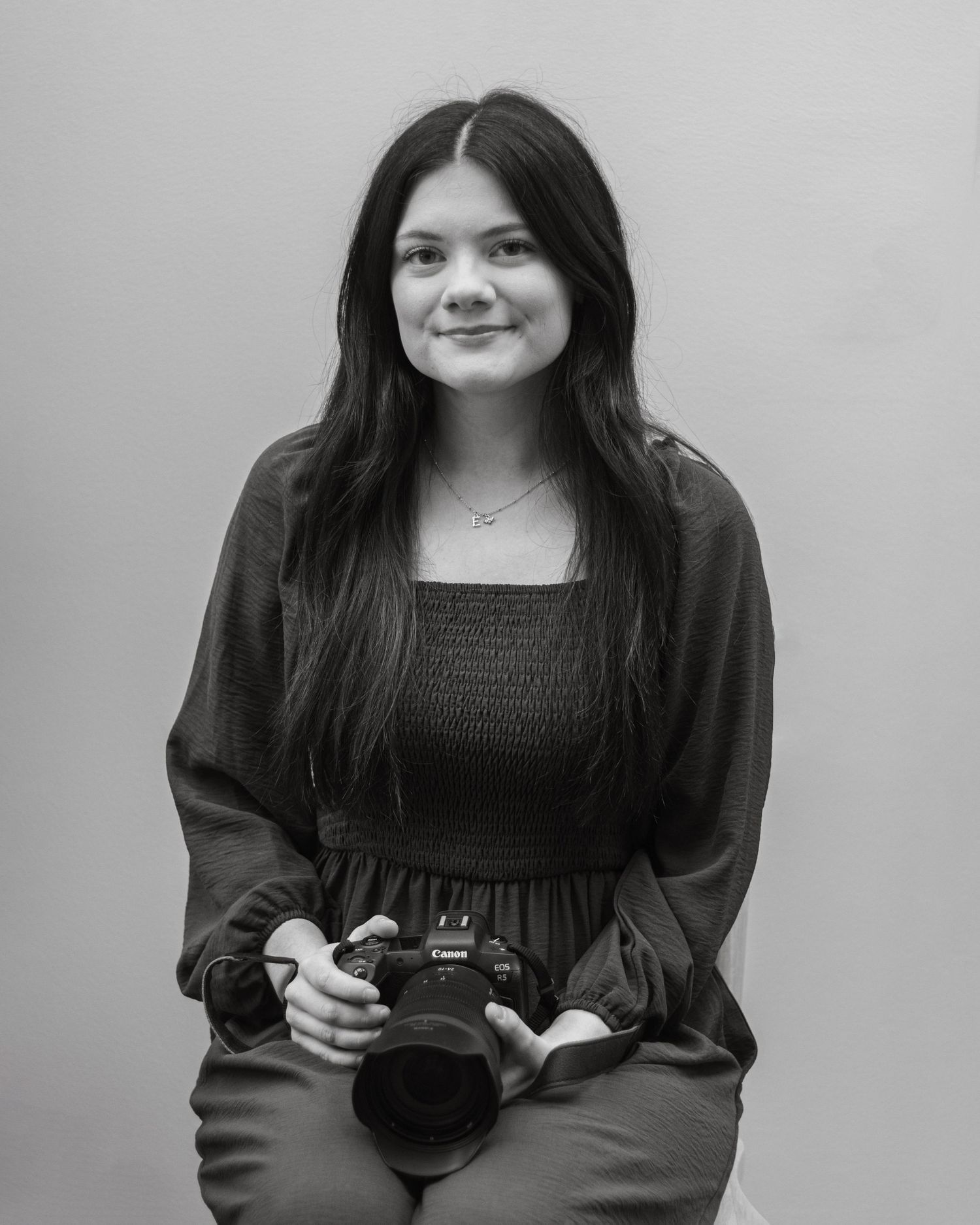 Evie, the owner of EvieSJPhotography, a Worcestershire wedding photography business sat in front of a white sheet.