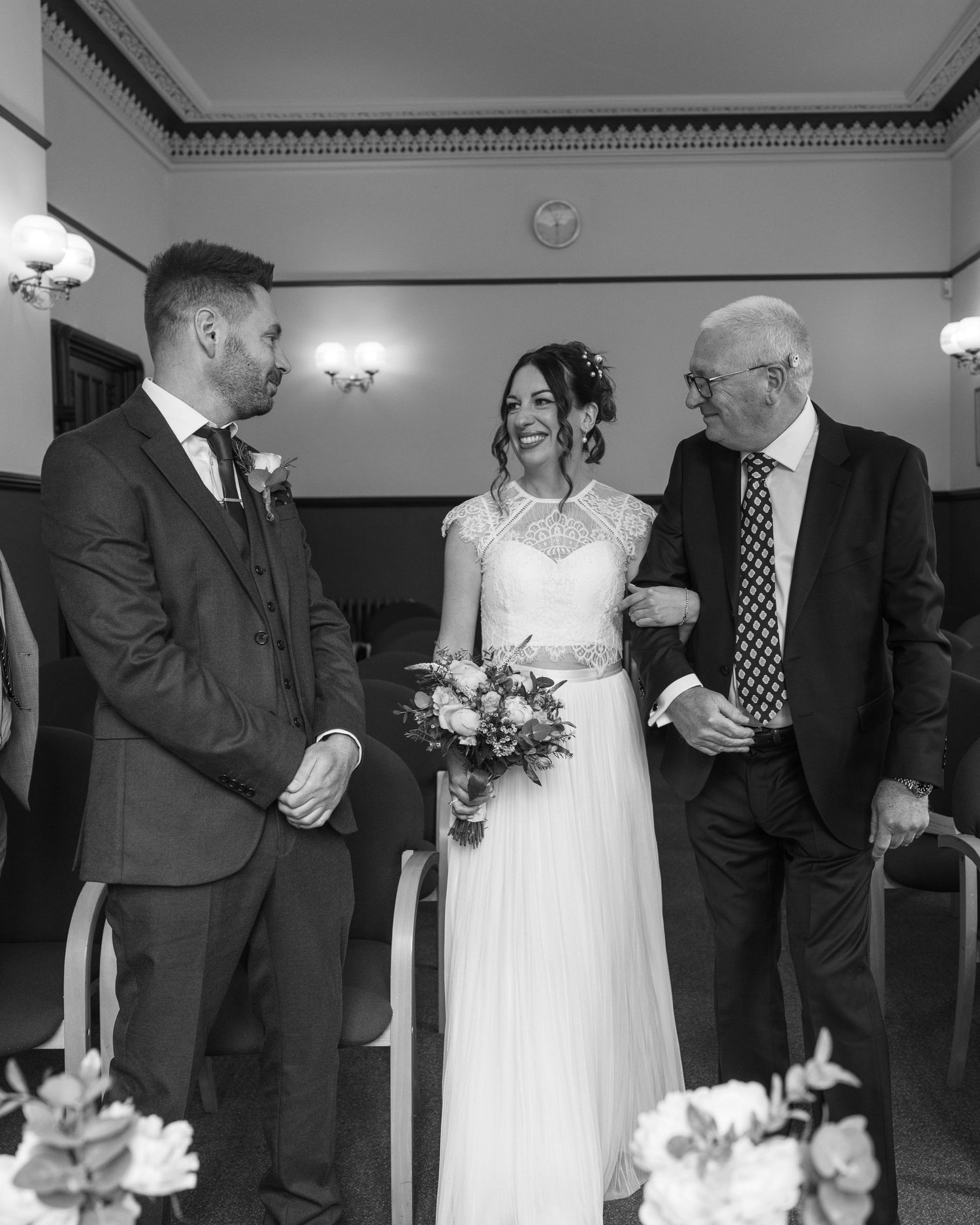 A bride and her father walking down the aisle to her future husband, captured by EvieSJPhotography.