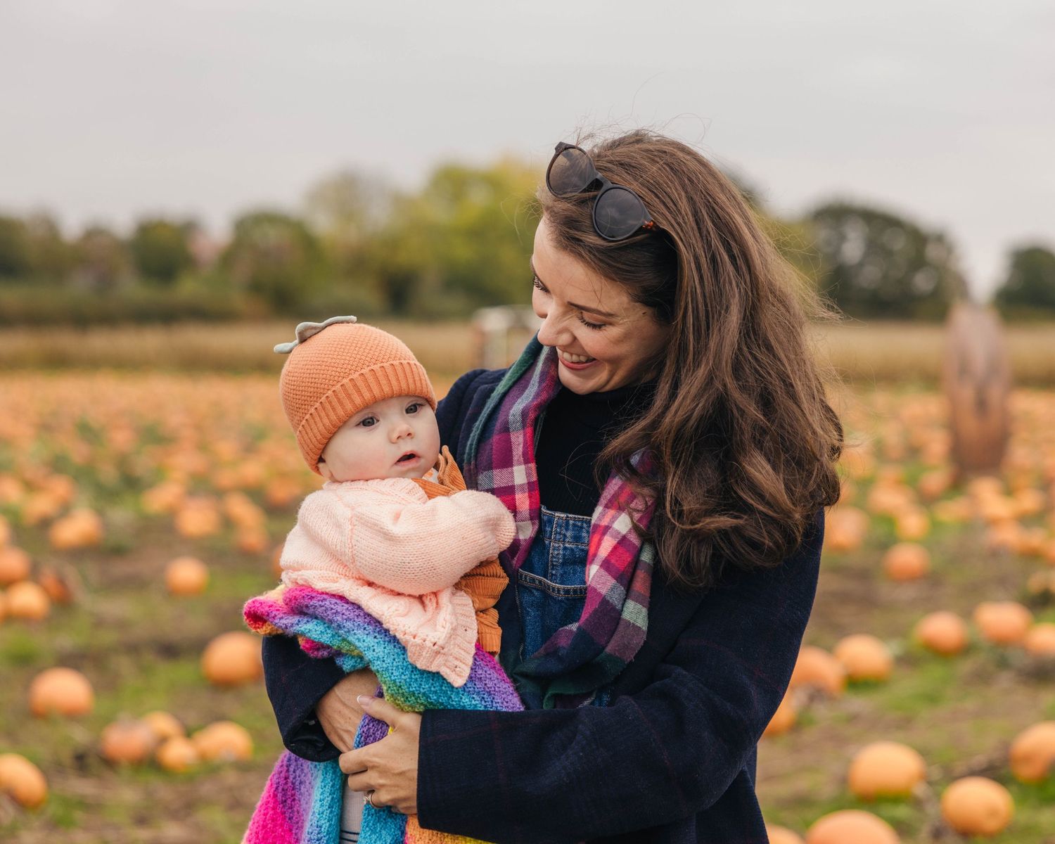 Mother and baby enjoying the pumpkin patch during an autumnal photoshoot captured by EvieSJPhotography.