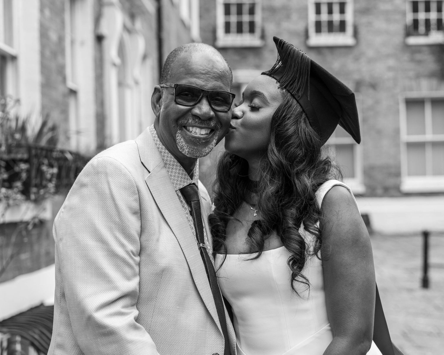 University graduate smiling in cap and gown during a graduation photoshoot with her family by EvieSJPhotography.