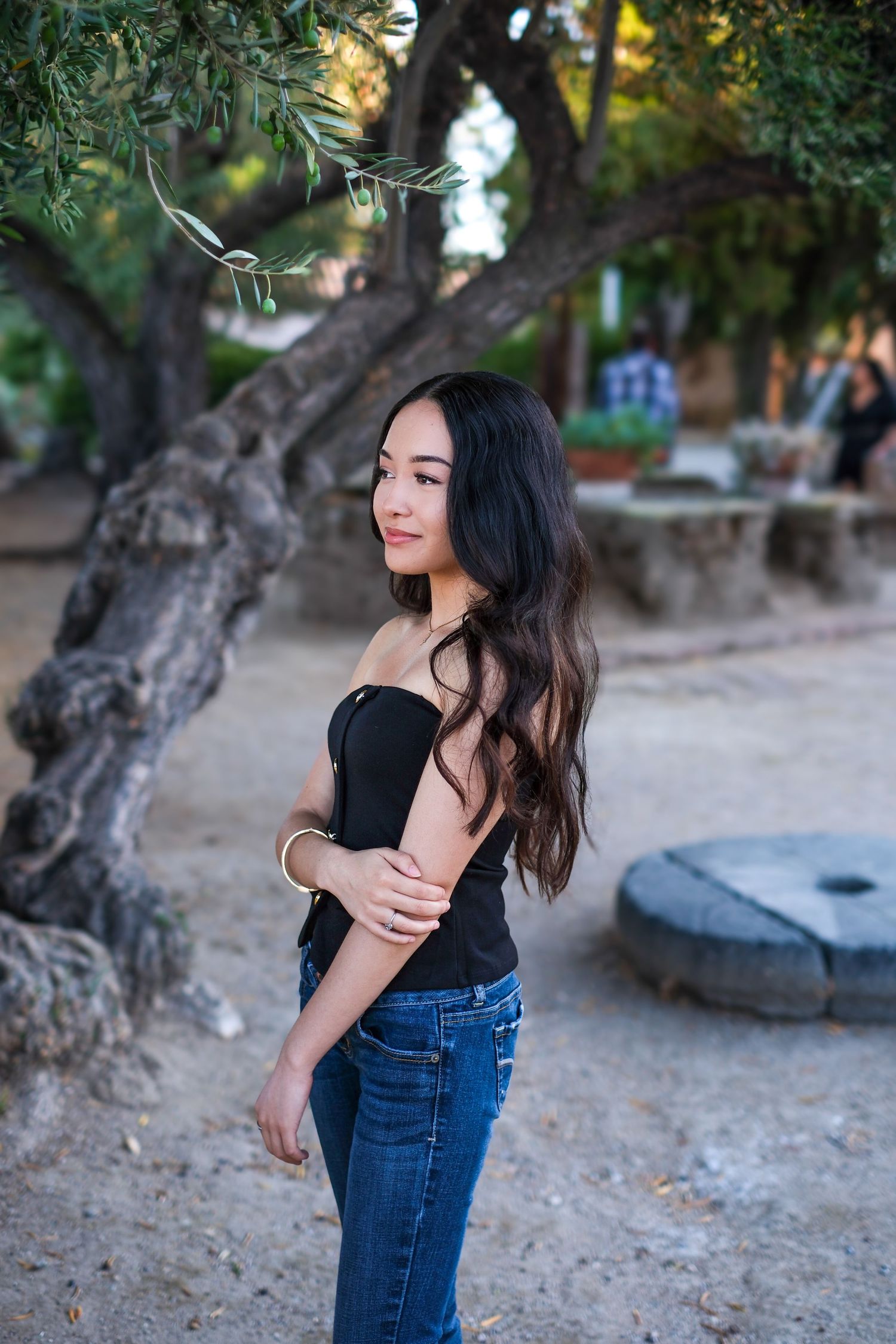 A casual outdoor photoshoot featuring a black top and jeans against a natural backdrop with trees.