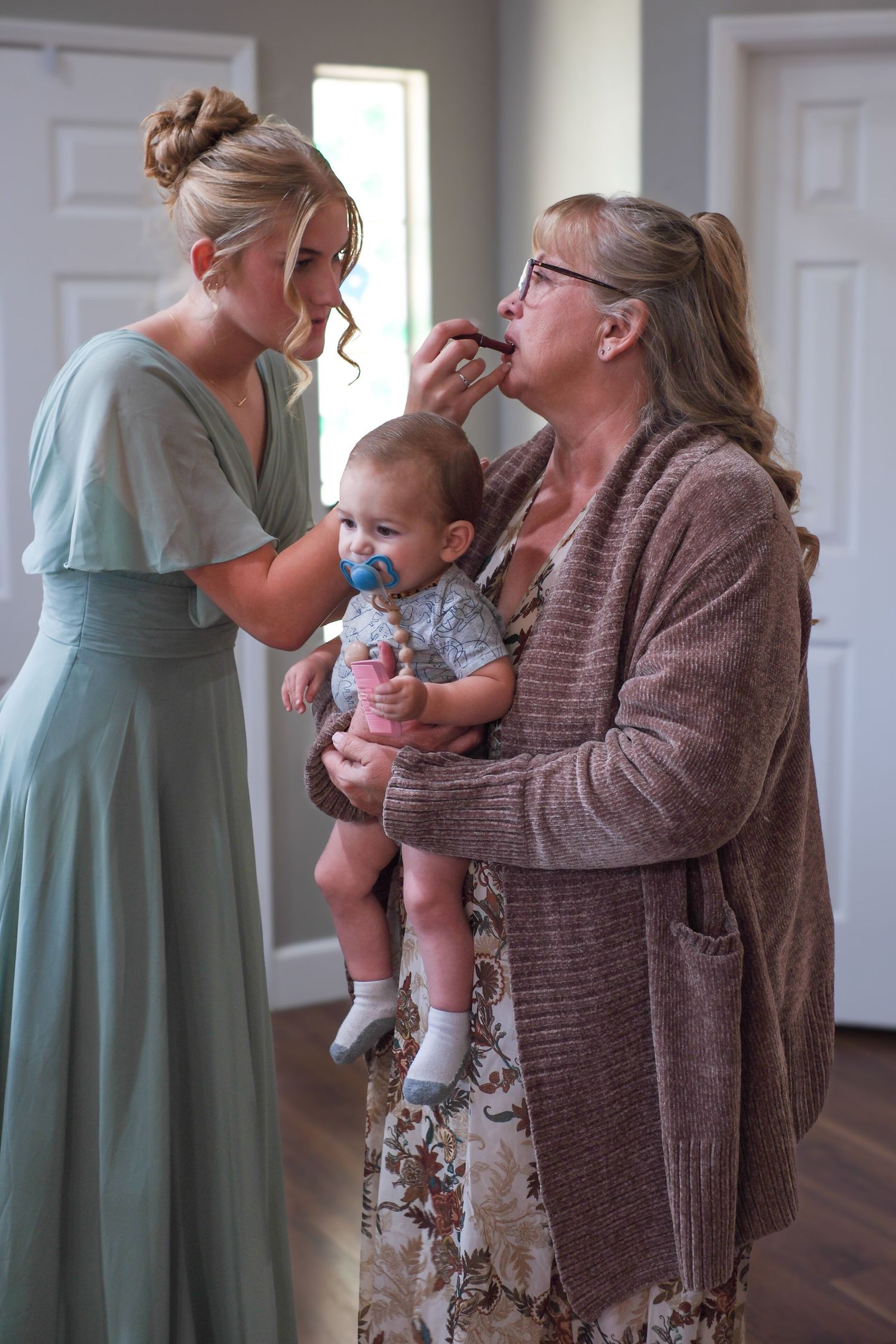 A candid series of emotional moments between a woman in a mint green dress and another in a brown sweater holding a baby.