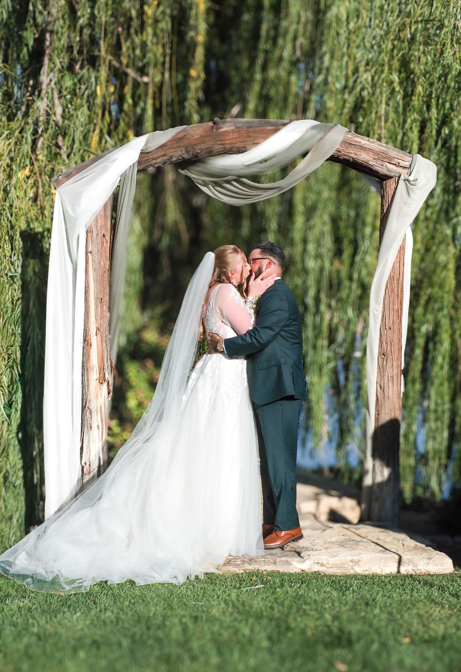 A romantic wedding photo sequence showing a couple embracing under a weeping willow tree in a garden setting.