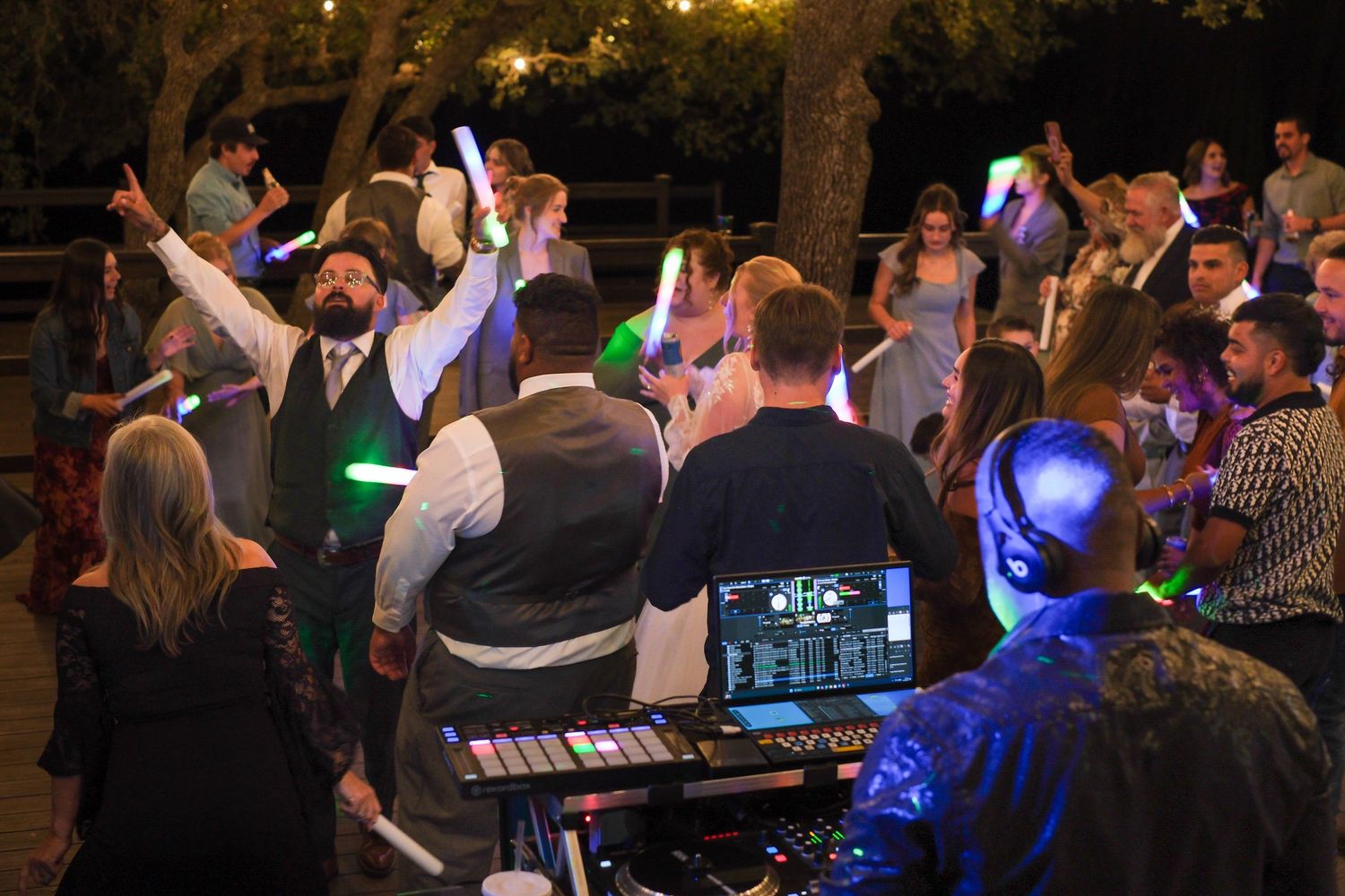A lively dance party scene with people dancing and socializing under colorful lighting at a nighttime event.