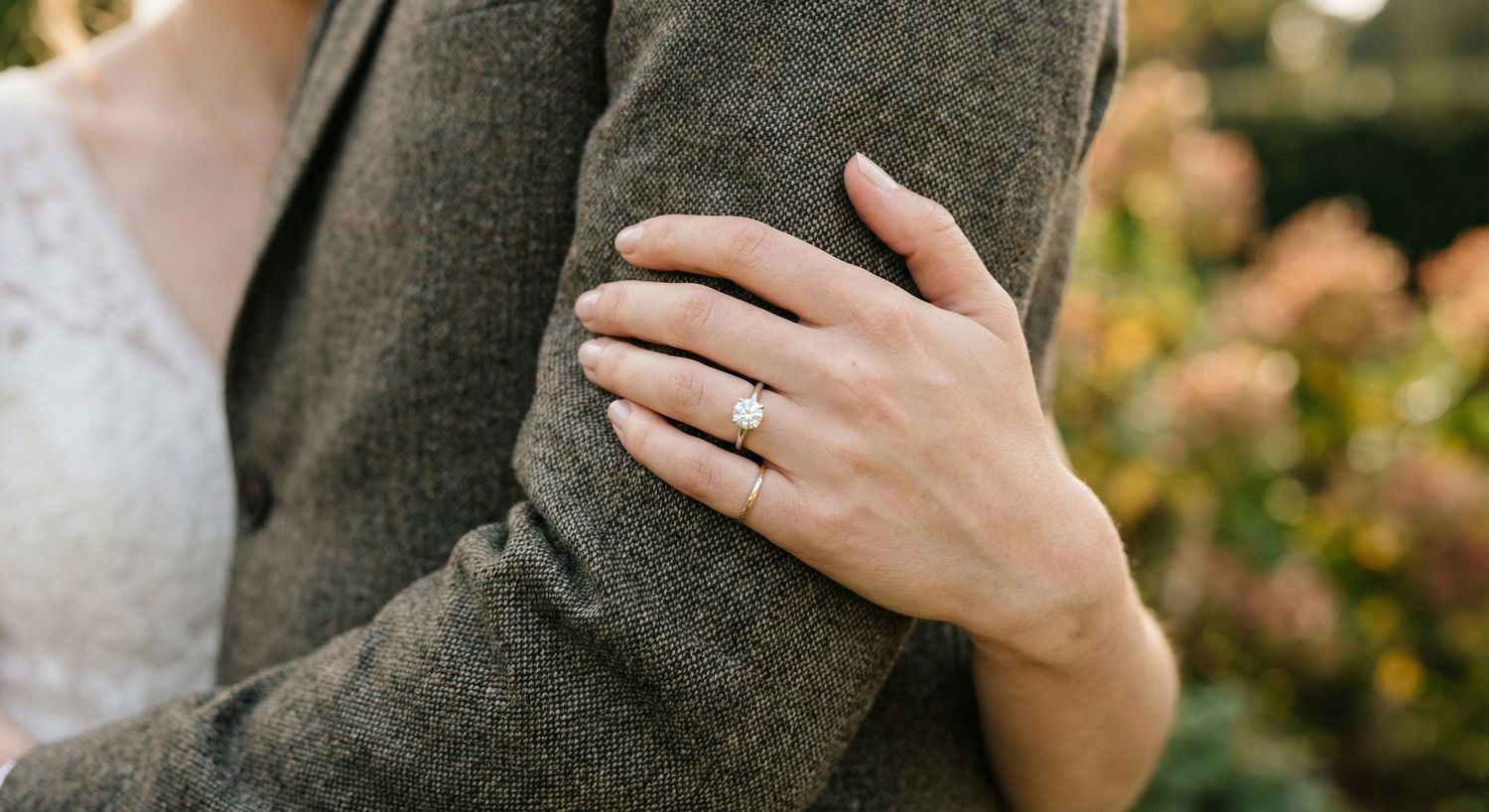 A couple holds hands while wearing gray and black winter coats during an intimate outdoor engagement photoshoot.