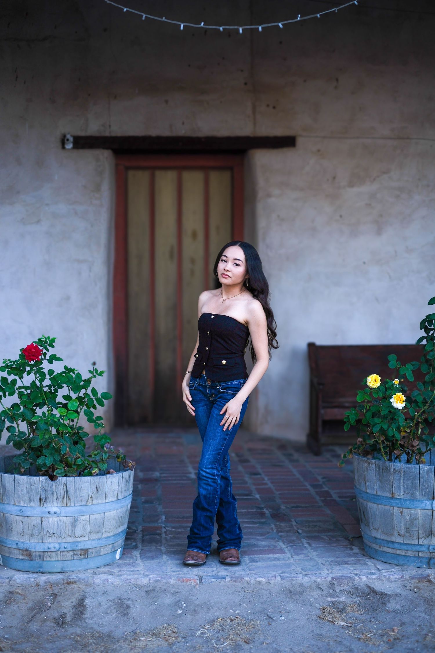 A series of photos showing someone posing next to rustic wooden barrel planters with flowers against an adobe wall.