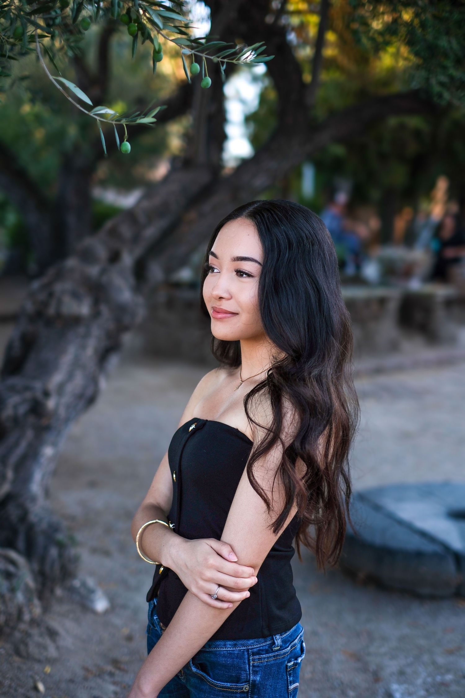 Natural light portrait session under trees with casual black top and blue jeans outfit.