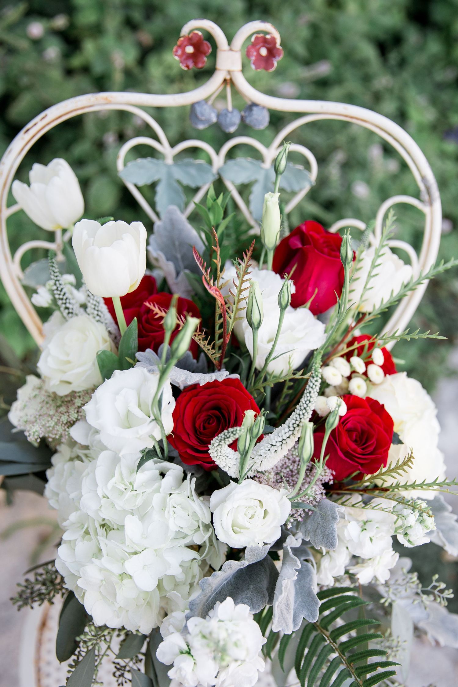 Elegant wedding floral arrangements featuring red roses and white hydrangeas with delicate greenery and silver accents.