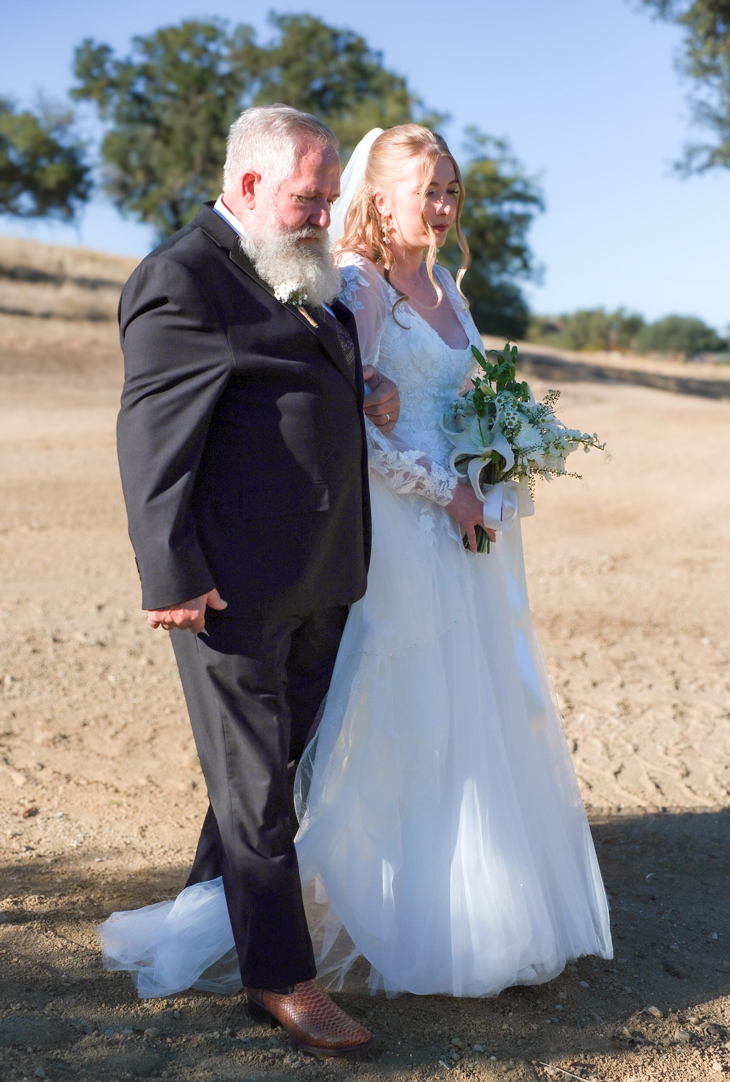 A couple shares a joyful moment together outdoors during their wedding ceremony on a sunny day.