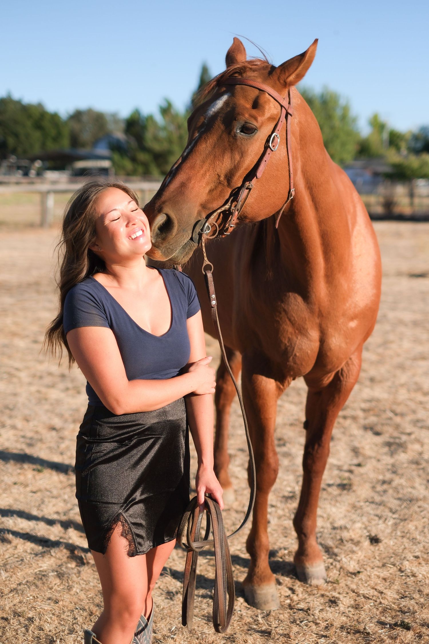 Person sharing an affectionate moment with a chestnut horse in a sunny field.
