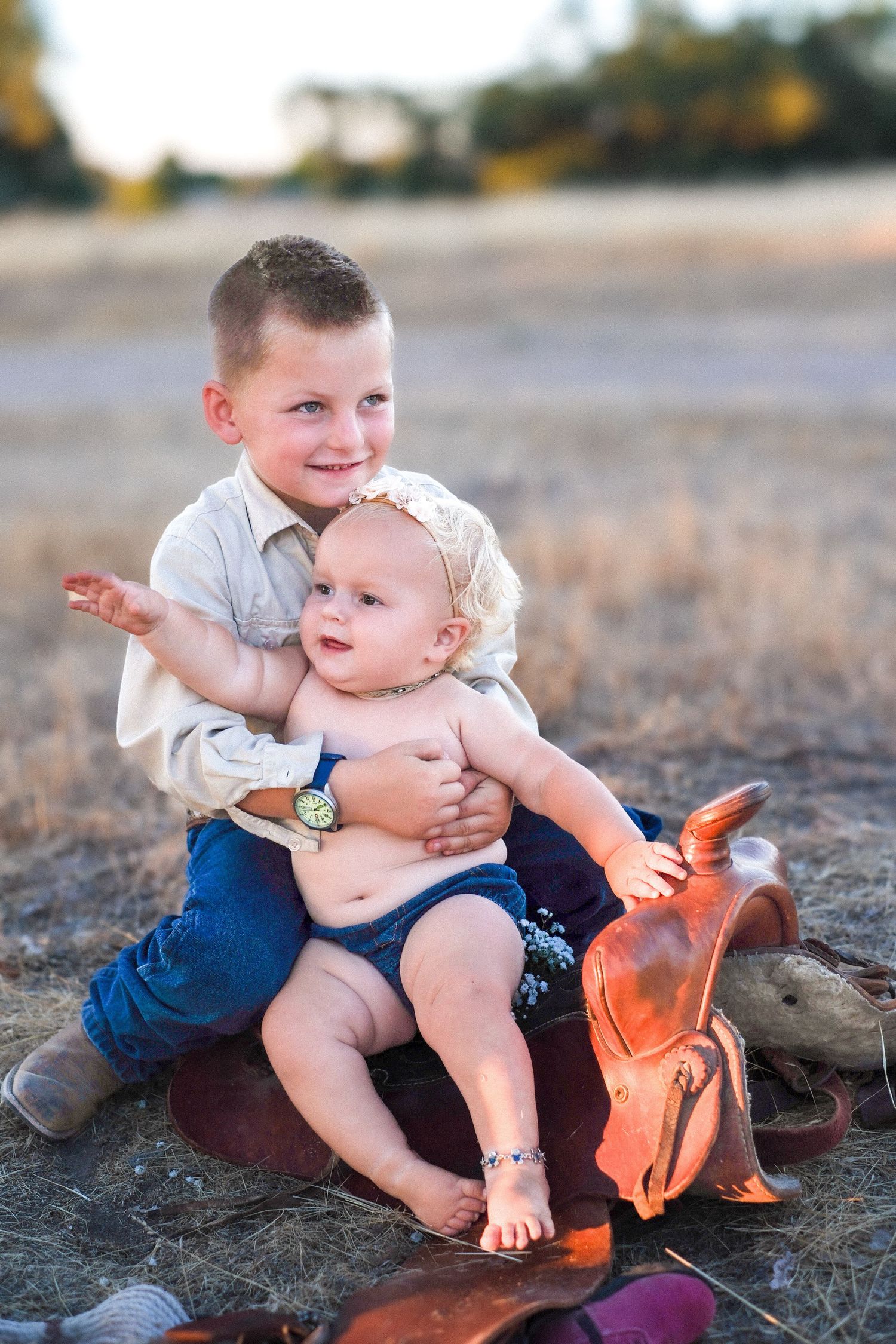 Two young children playing together outdoors on a sunny day with one holding a stuffed orange toy.
