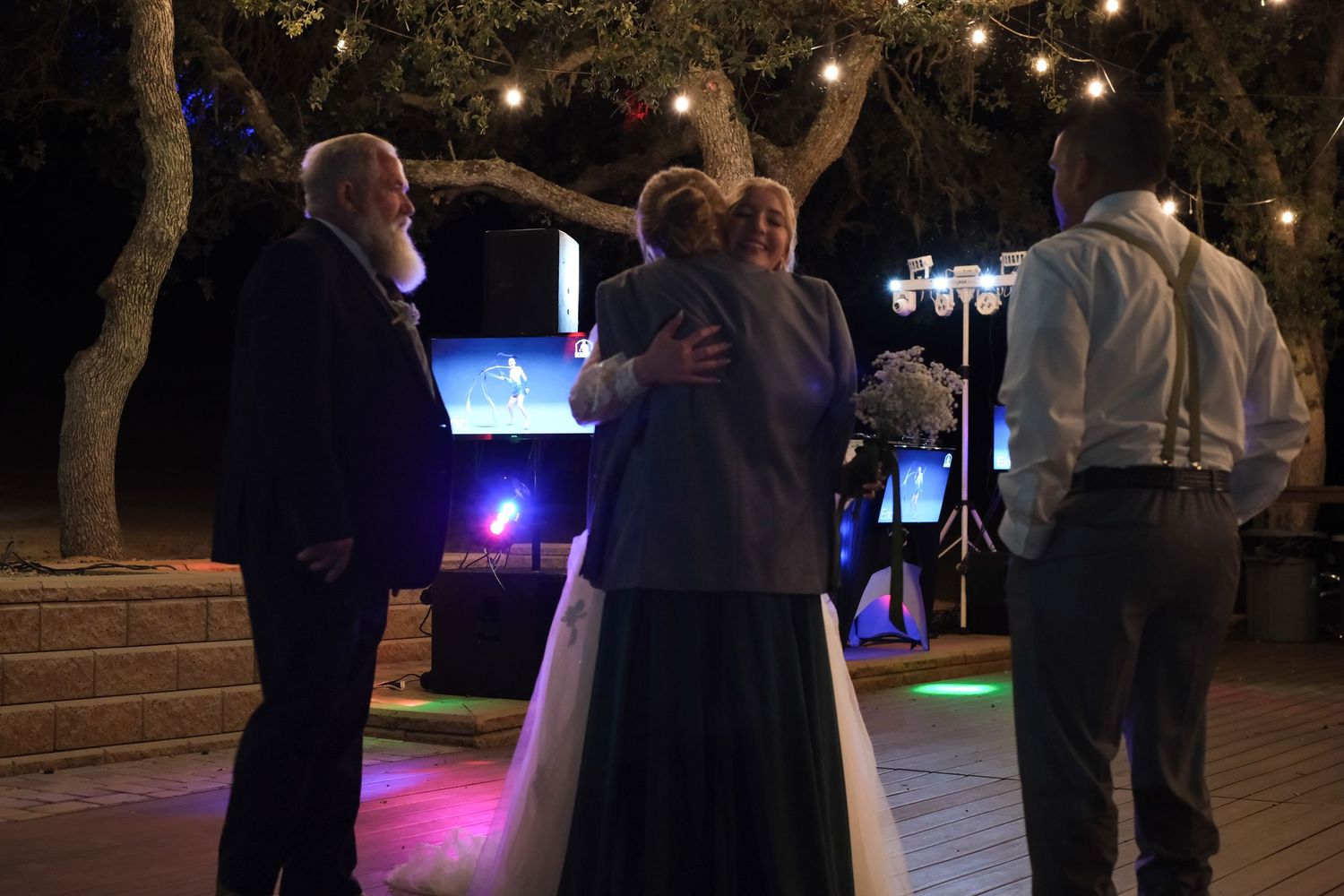 Wedding reception dance floor illuminated with string lights and blue ambient lighting at night.
