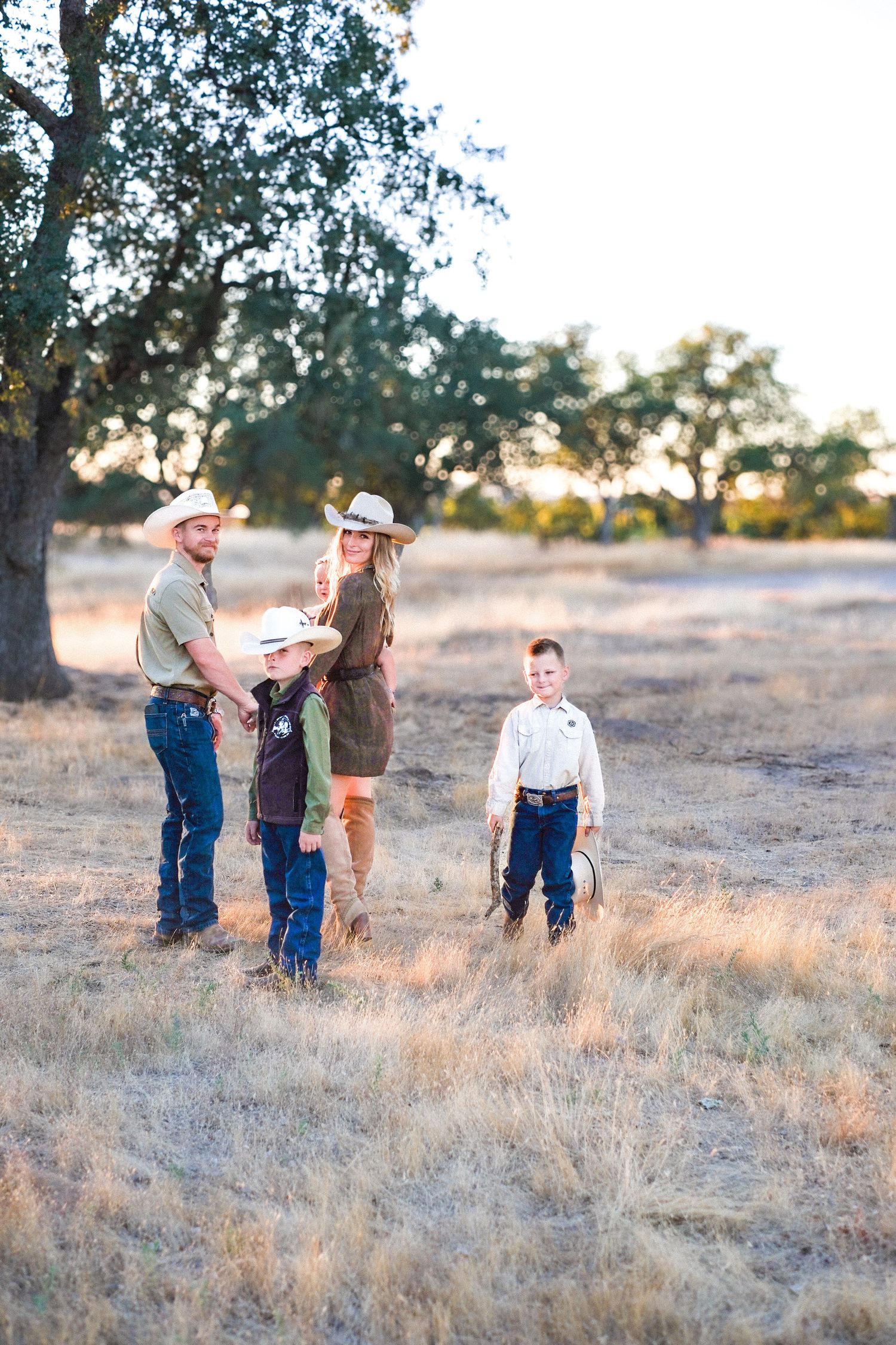 Family having fun together in a golden field at sunset, creating playful moments in nature.