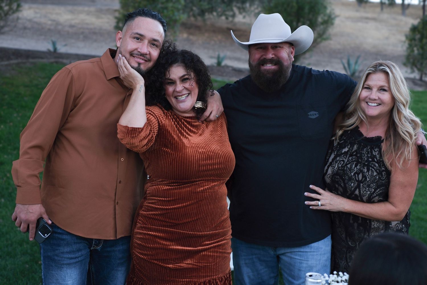 Group photo of friends in earth-toned clothing posing casually outdoors.
