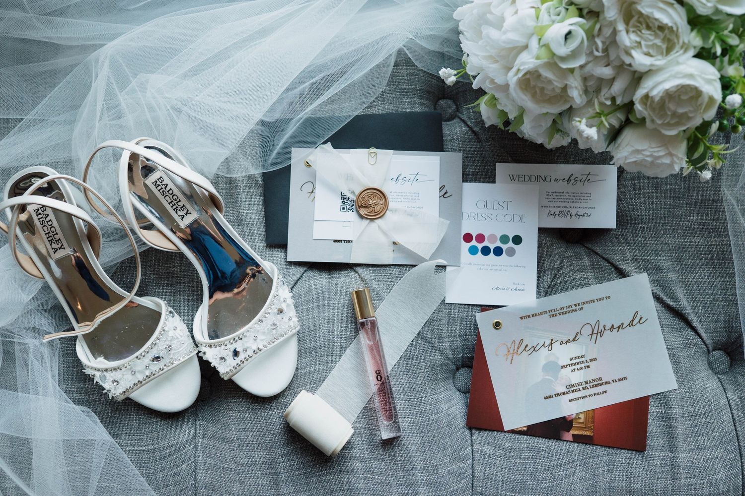 Elegant wedding flat lay with white heels, perfume, invitations, wax seal, watercolor palette, and floral bouquet.