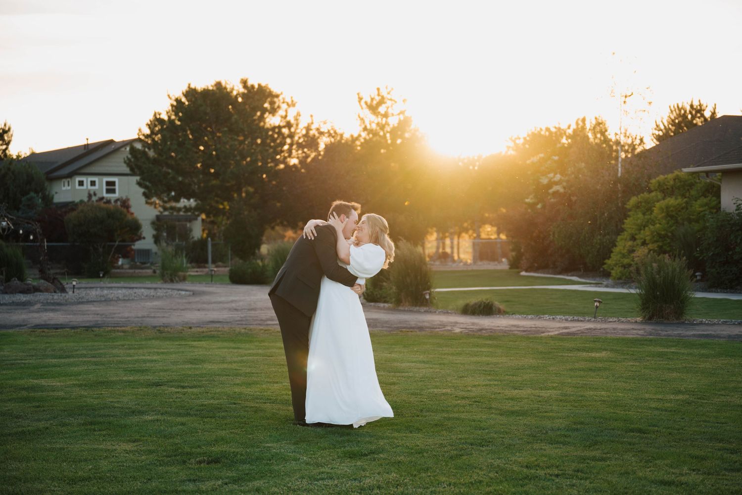 Sunset wedding photos taken on a spacious green lawn.