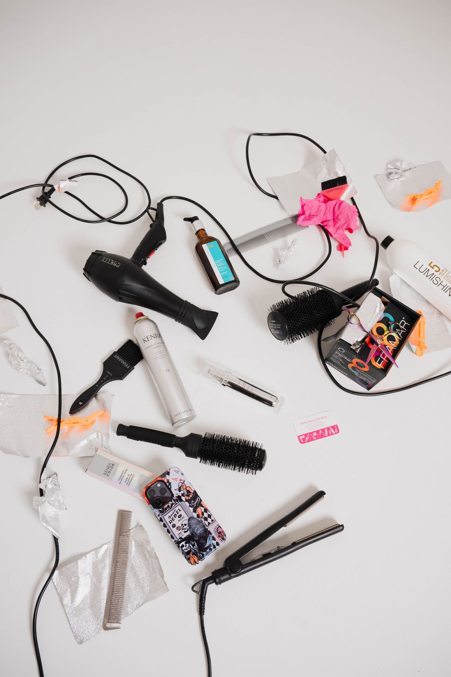 Flat lay of hair styling tools and products arranged on white background.